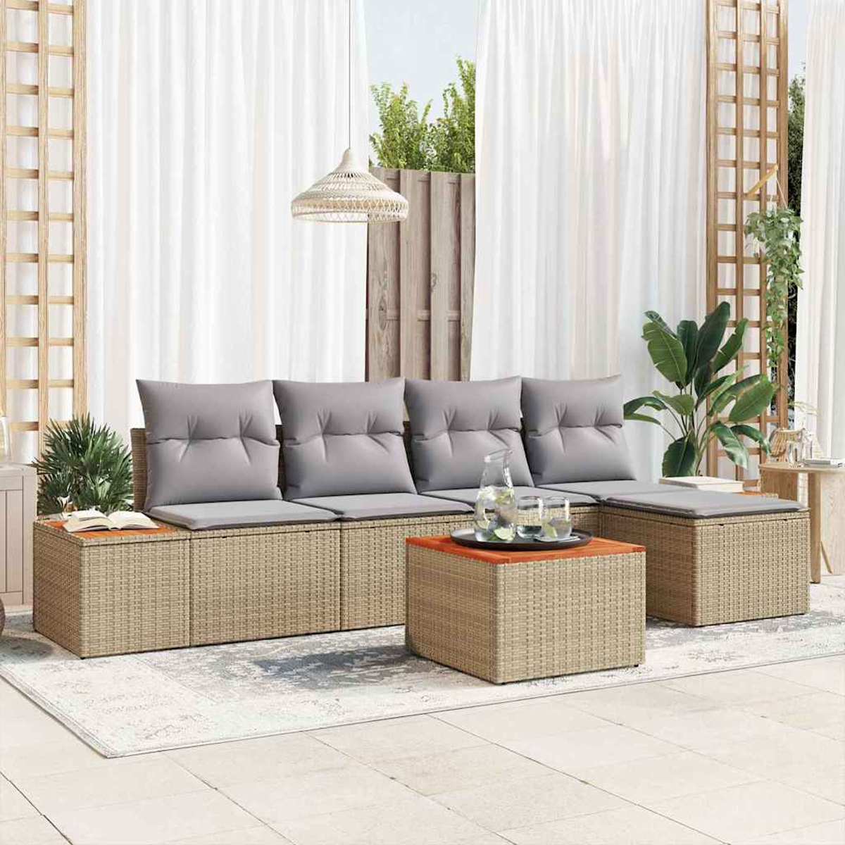 Gartensitzgruppe auf einer Terrasse. Sie umfasst ein Sofa, eine Ottomane und einen Couchtisch aus gewebtem Material mit grauen Kissen.