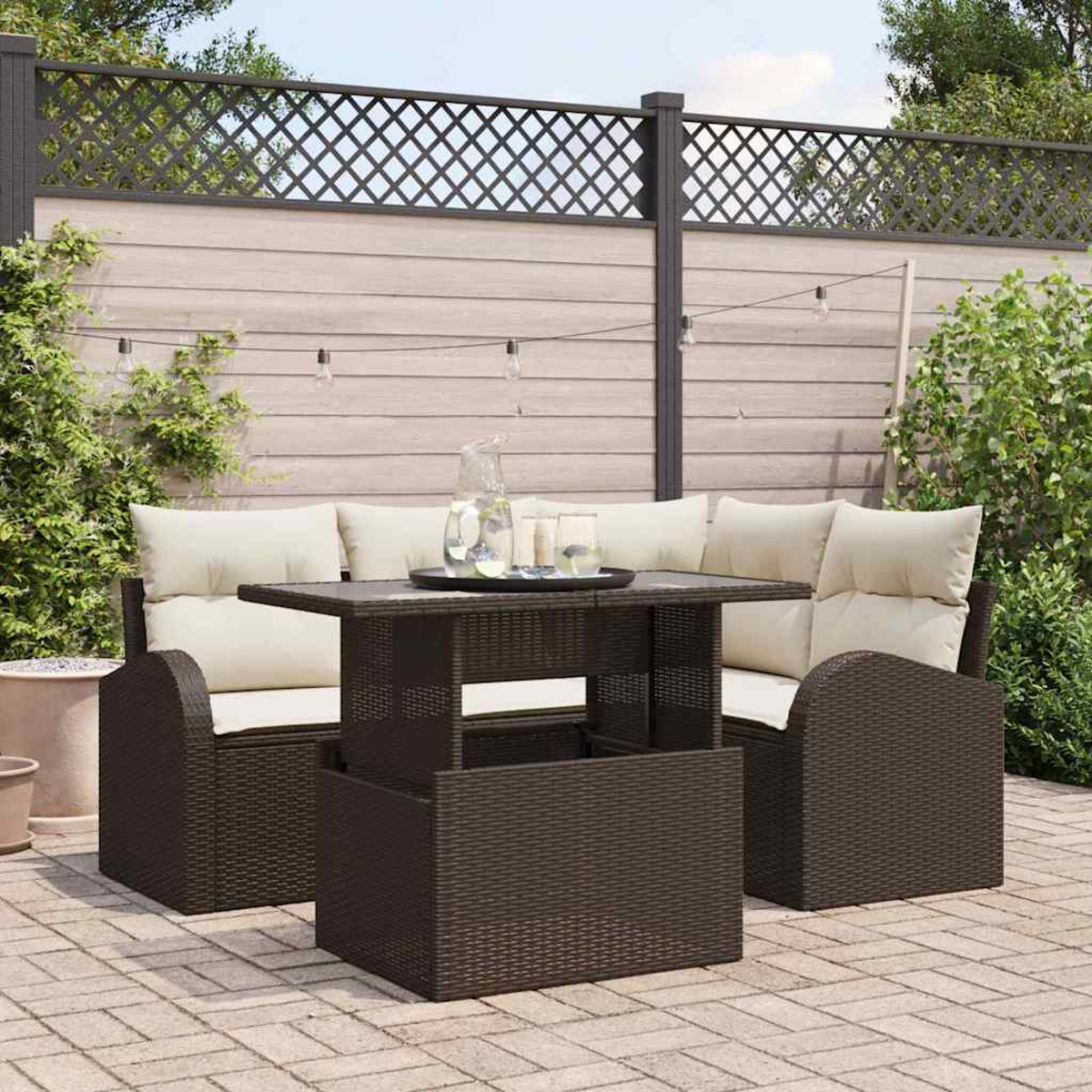 Gartenmöbel-Set mit braunen Korbstühlen, beigen Kissen, Tisch mit Gläsern und Zaun im Hintergrund.