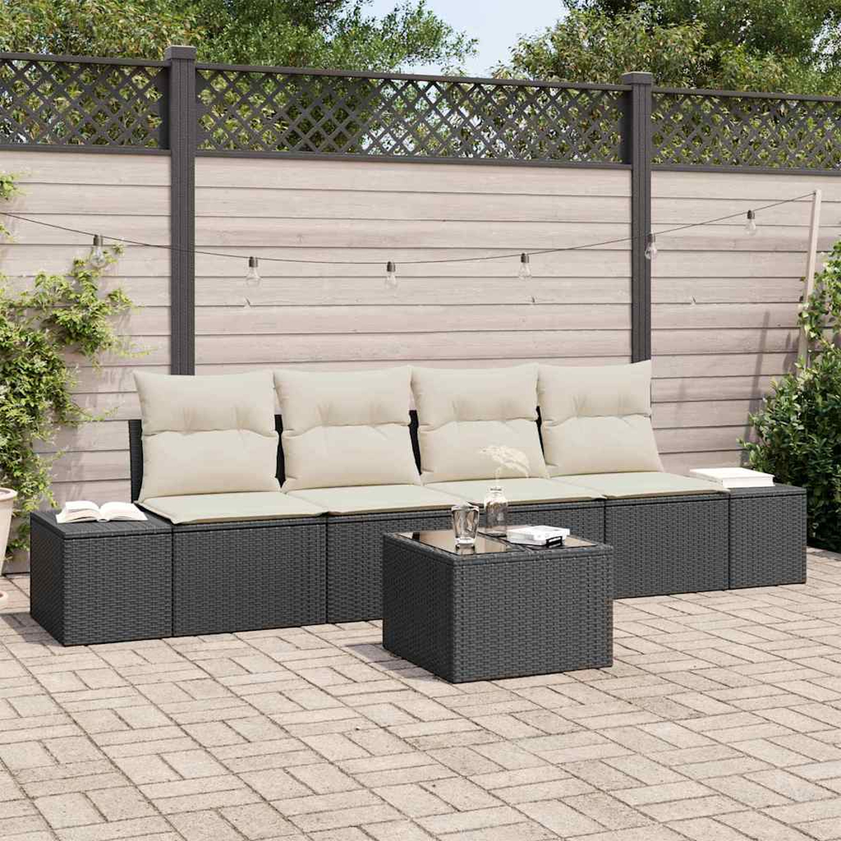Outdoor-Sitzgruppe mit dunkelgrauem Korbsessel, beigen Kissen und einem Couchtisch mit Glasplatte auf einer Ziegelterrasse.