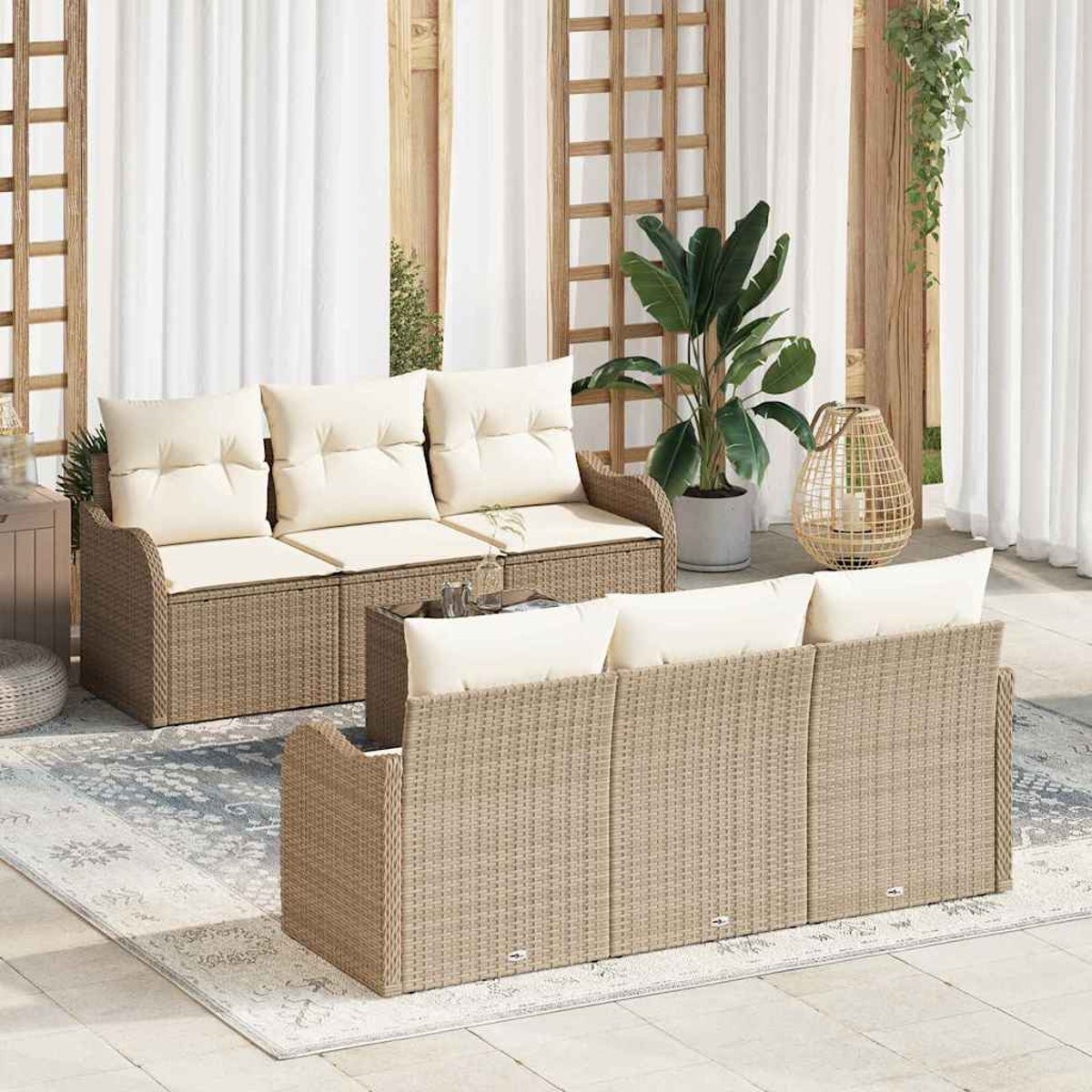 Outdoor-Rattan-Möbelset mit cremefarbenen Kissen. Enthält zwei Sofas, einen Couchtisch und einen Teppich, vor dem Hintergrund weißer Vorhänge.