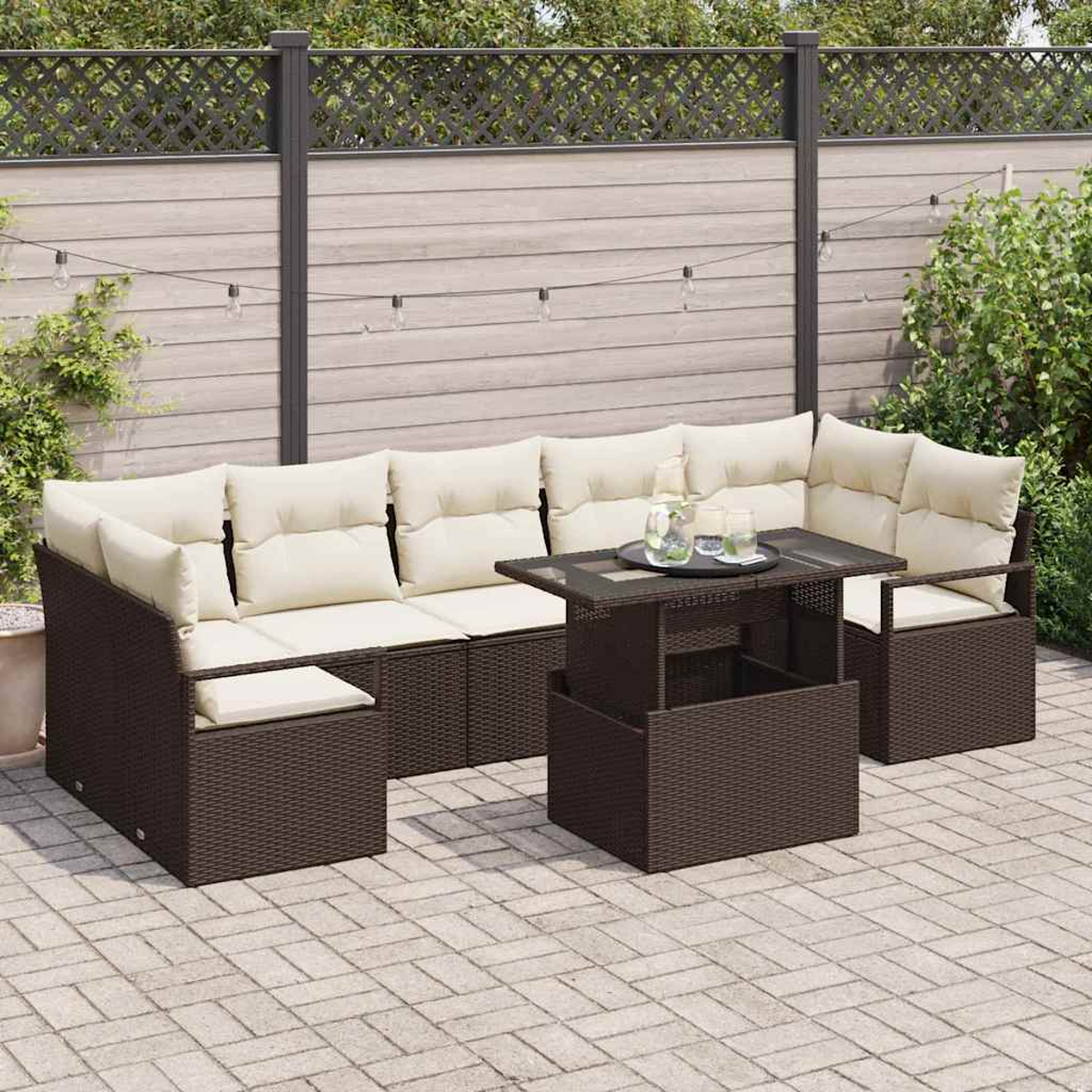 Gartenmöbel-Set mit braunem Korbsessel, cremefarbenen Kissen und einem höhenverstellbaren Couchtisch. Hintergrund mit Zaun und Pflanzen.