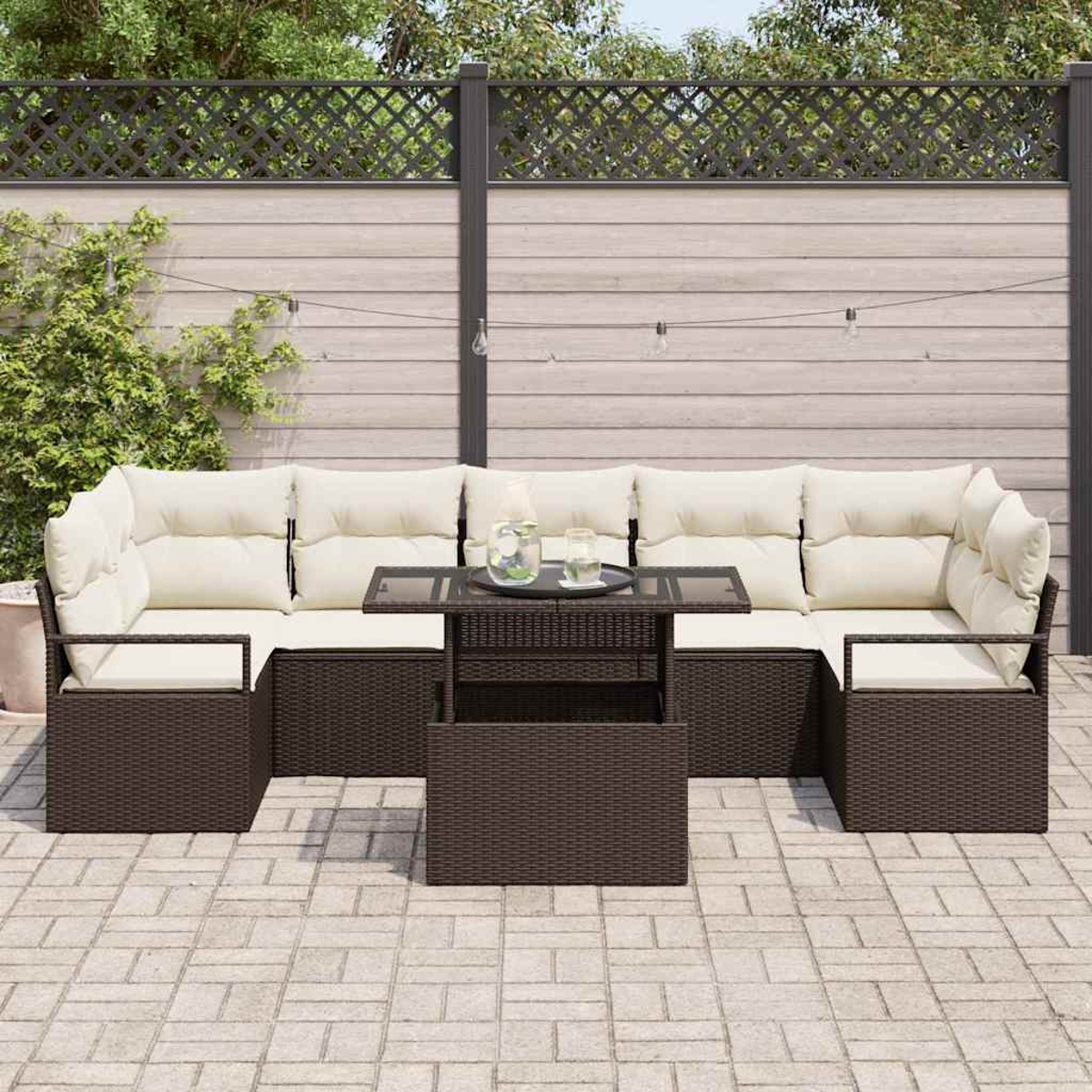Garten-Sitzgruppe mit braunen Korbflechtrahmen und cremefarbenen Kissen. Davor steht ein Couchtisch mit Glasplatte. Im Hintergrund ist ein Zaun.