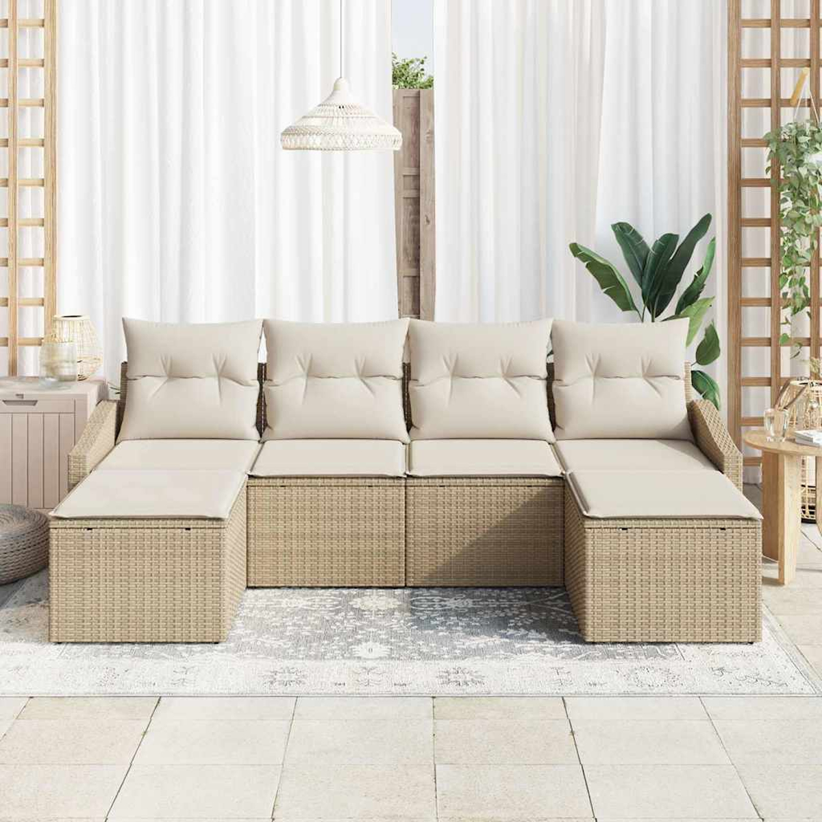 Ein beiges Rattan-Ecksofa mit cremefarbenen Kissen steht auf einem gemusterten Teppich. Weiße Vorhänge, eine Hängeleuchte und Pflanzen befinden sich im Hintergrund.