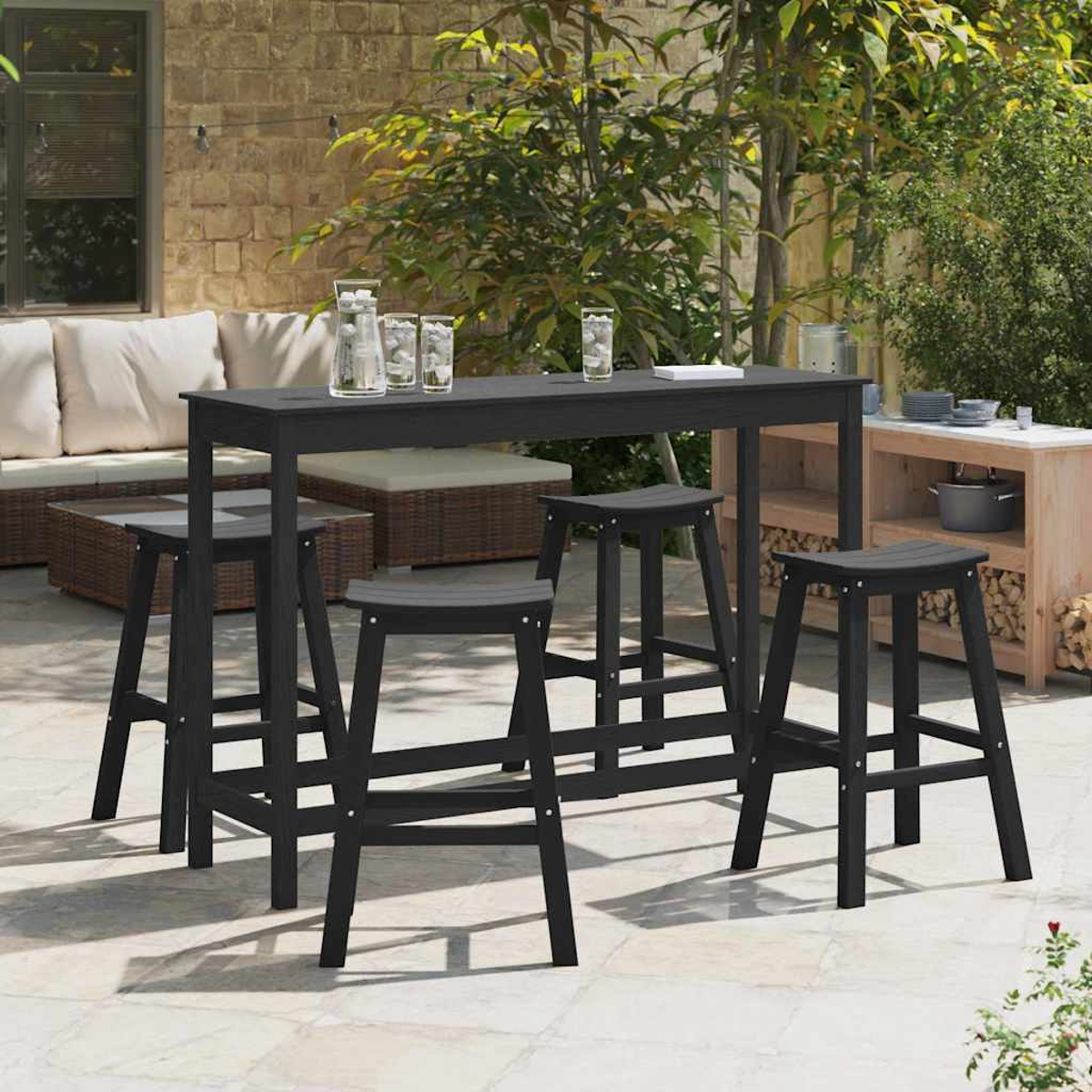 Outdoor-Bar-Set. Schwarzer Bartisch und Hocker auf einer Terrasse. Im Hintergrund befinden sich ein Sofa und Pflanzen. Gläser auf dem Tisch.