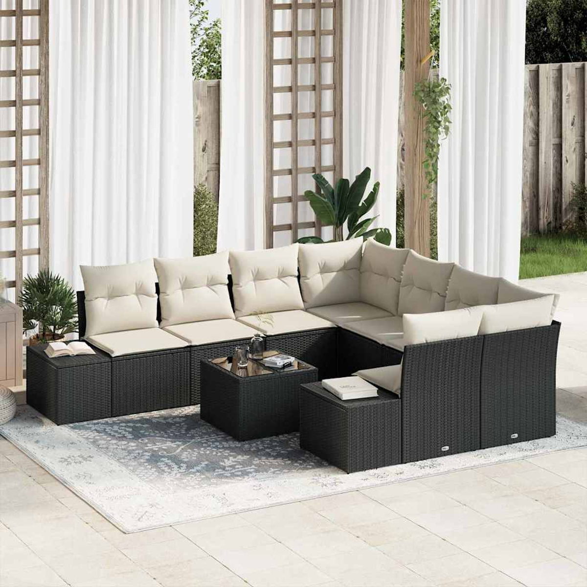 Ein Ecksofa im Freien mit beigefarbenen Kissen steht auf einer Terrasse mit Teppich und Vorhängen. Kleine Tische und Pflanzen sind im Bild.