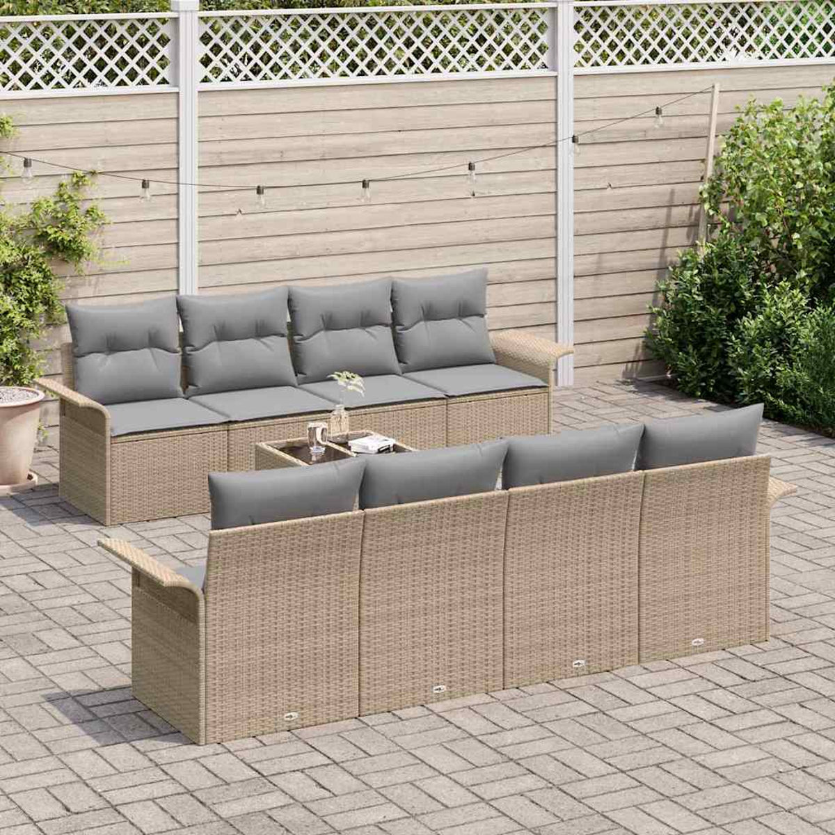 Rattan-Terrassenmöbel-Set. Zwei Sofas mit grauen Kissen, ein kleiner Tisch und ein Zaun im Hintergrund. Auf einer gepflasterten Terrasse.