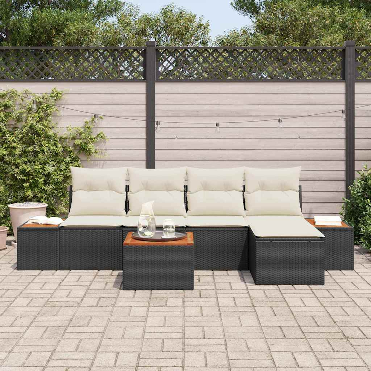 Szene im Freien mit einem schwarzen Korbsessel mit cremefarbenen Kissen, einem Couchtisch und einer Backstein-Terrasse. Hintergrund: Holzzaun.