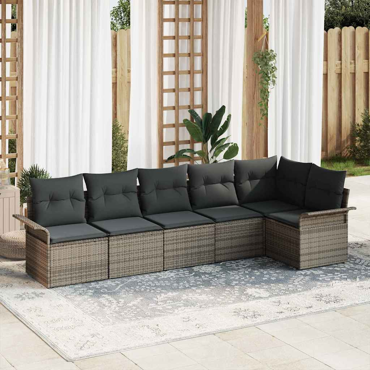 Outdoor-Ecksofa mit grauen Kissen. Es steht auf einem gemusterten Teppich, mit weißen Vorhängen und Holzzaun im Hintergrund.
