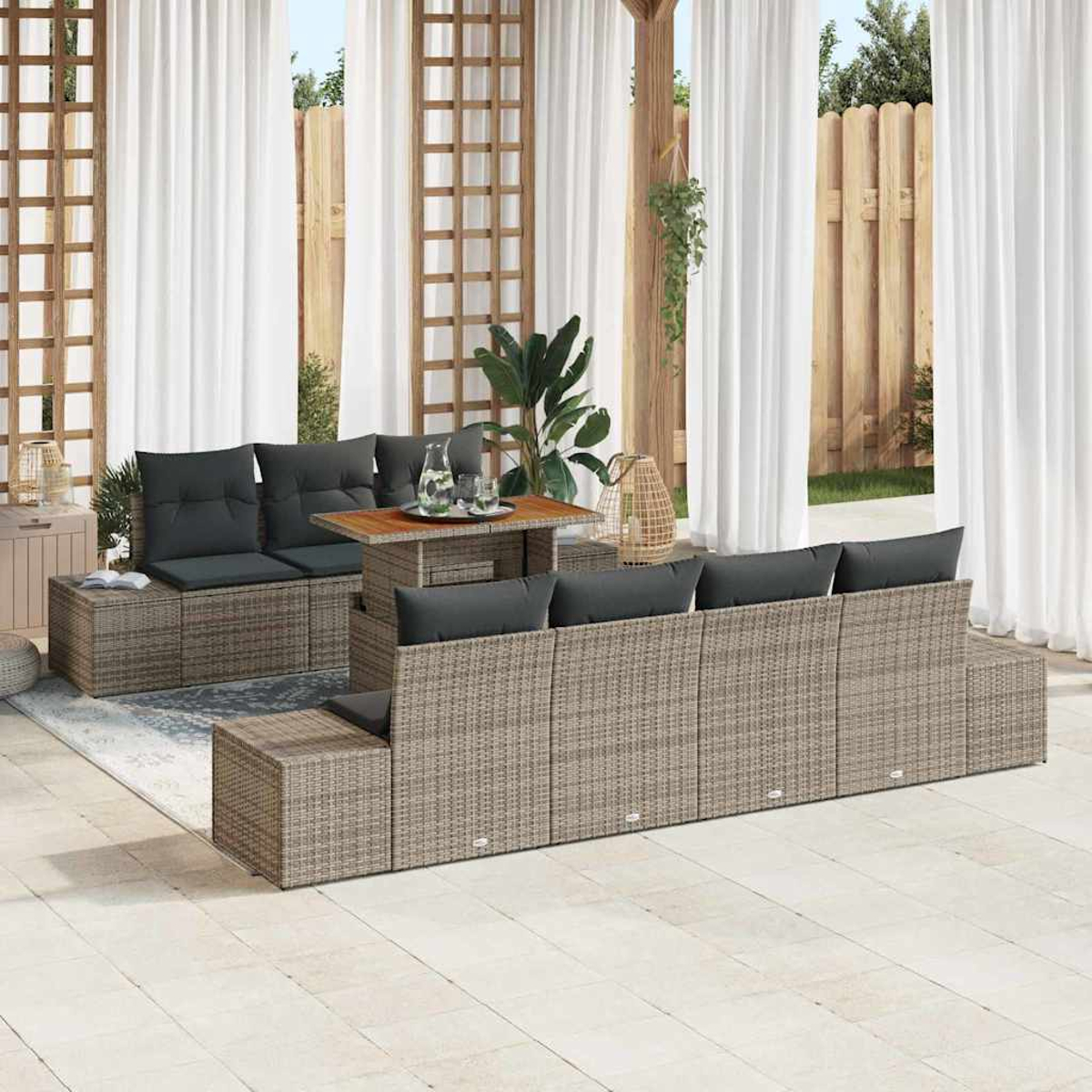 Gartenmöbel-Set. Korbsessel mit grauen Kissen, kleiner Holztisch, weiße Vorhänge und Holzzaun im Hintergrund.