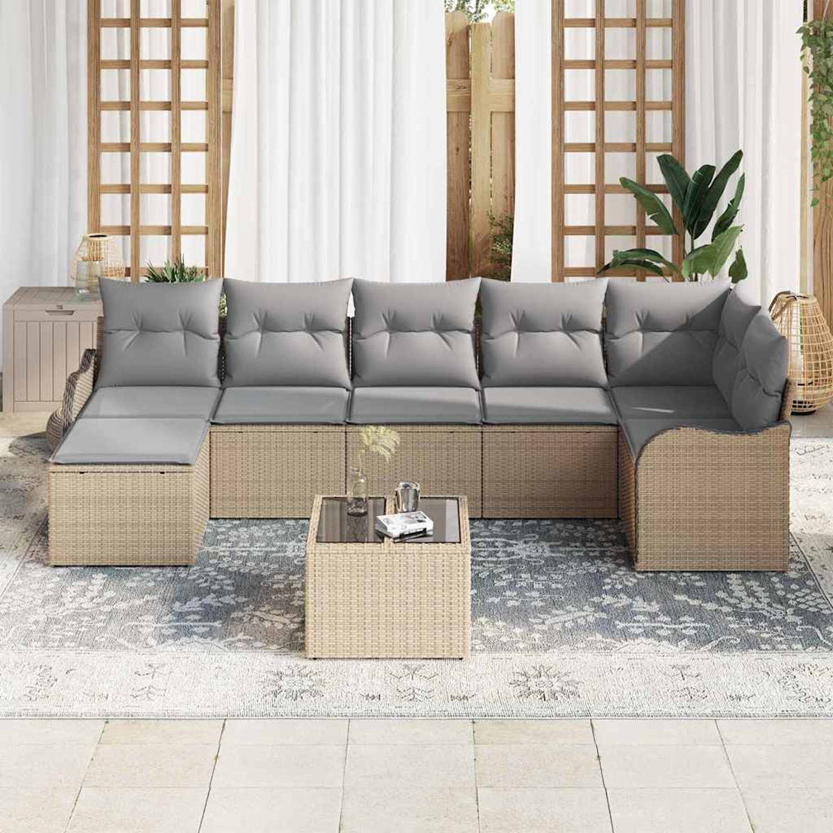 Un sofá seccional exterior con cojines grises está sobre una alfombra estampada. Una pequeña mesa está al frente. Cortinas blancas y celosías de madera al fondo.