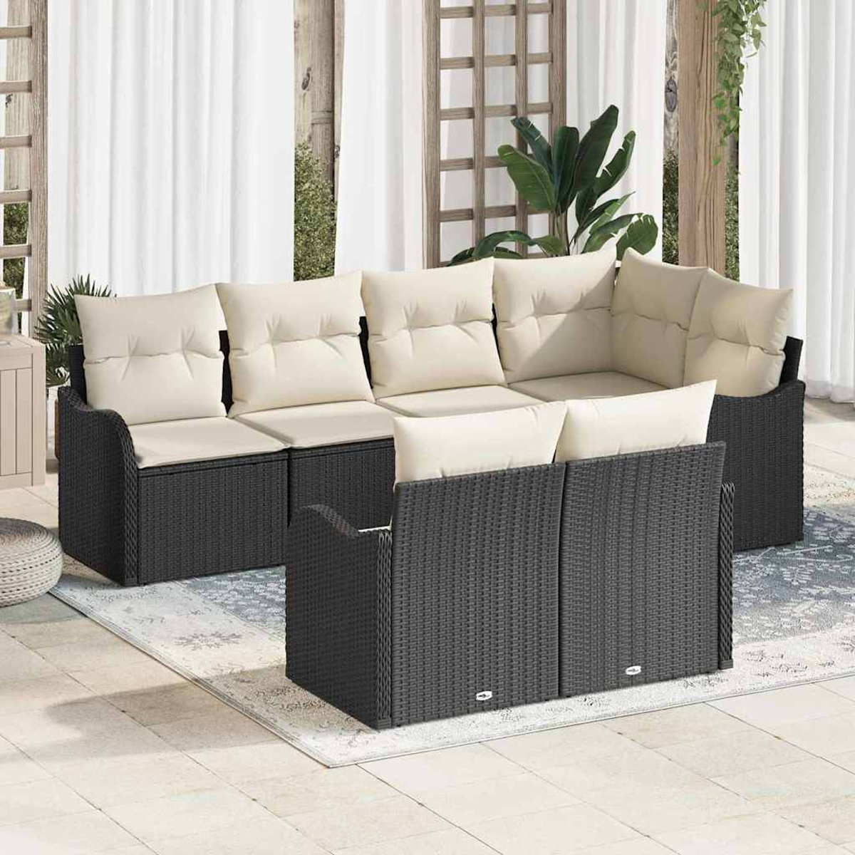 Garten-Sitzgruppe mit schwarzem Korbgeflecht und beigen Kissen, auf einer Terrasse mit weißen Vorhängen und einem Teppich.