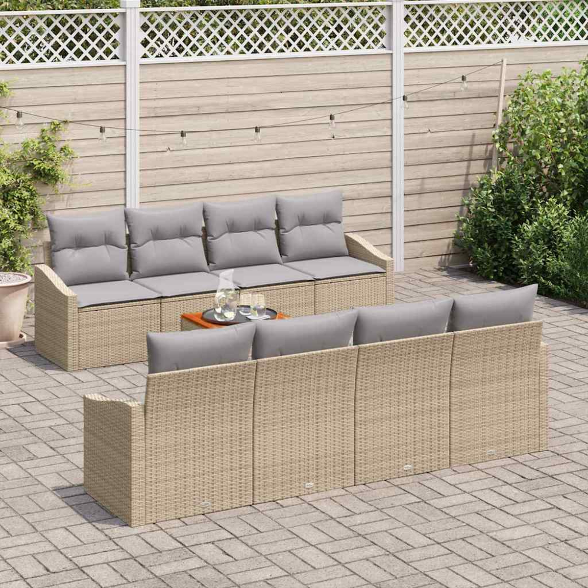 Outdoor-Patio-Setting mit zwei Rattansofas mit grauen Kissen und einem kleinen Tisch. Ein weißer Zaun und Grünzeug befinden sich im Hintergrund.