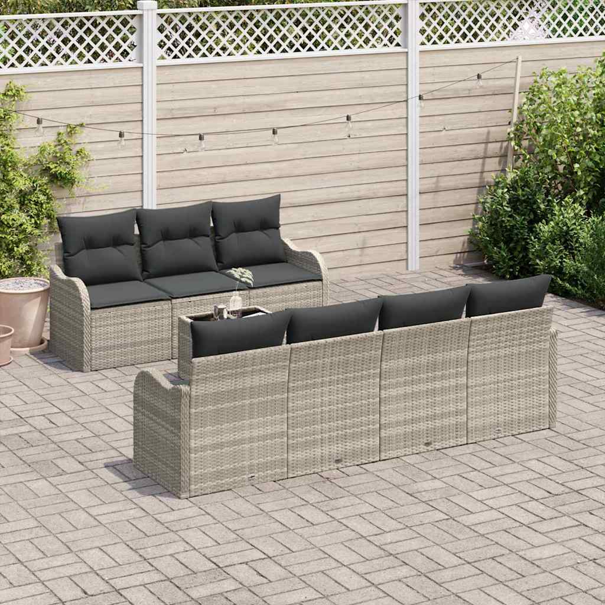 Zwei Korbs Sofas mit schwarzen Kissen stehen auf einer Terrasse. Ein weißer Zaun und eine Holzwand bilden den Hintergrund.