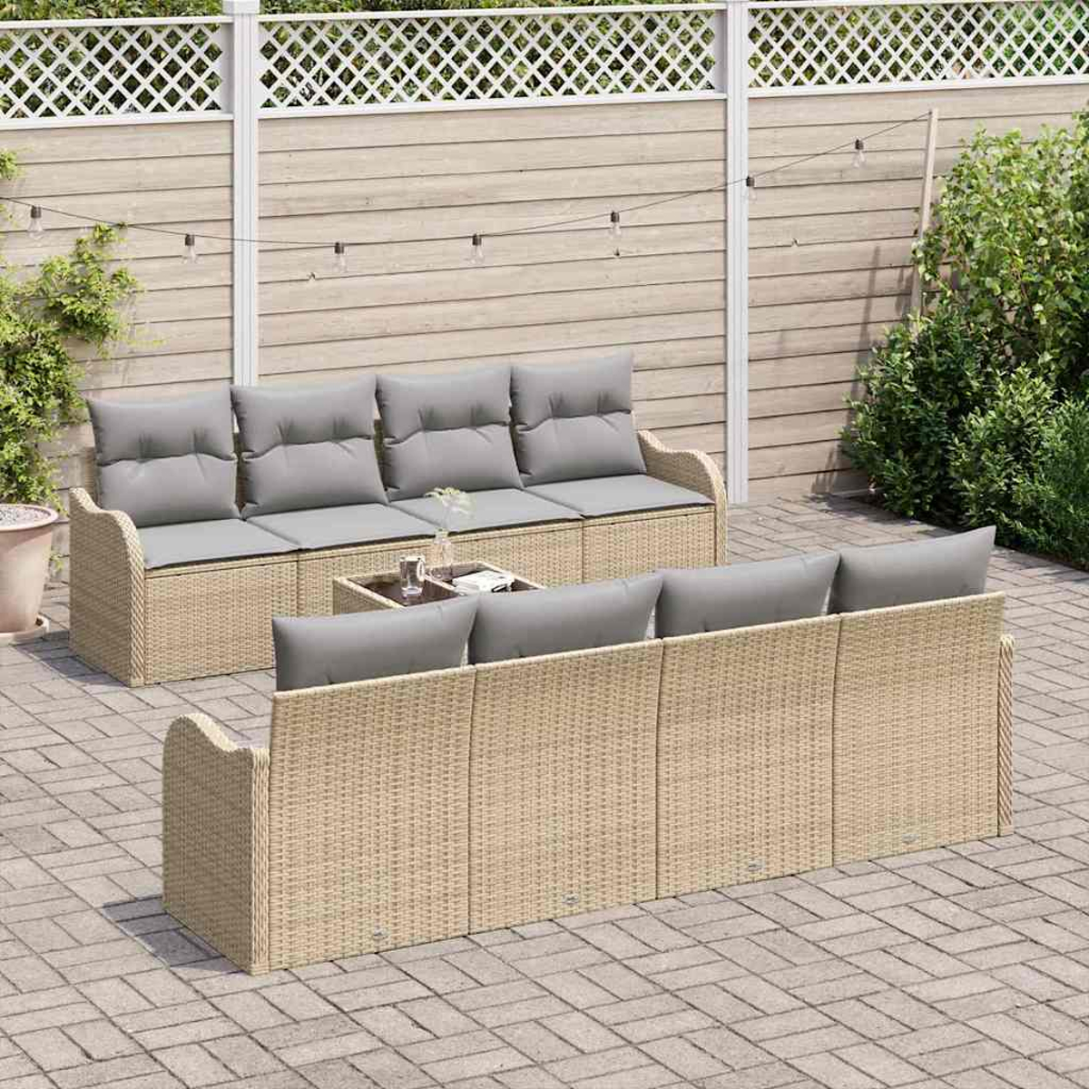 Gartenmöbel-Set. Korbsessel mit grauen Kissen, ein kleiner Tisch und Lichterketten, alles auf einer Ziegelpatio.