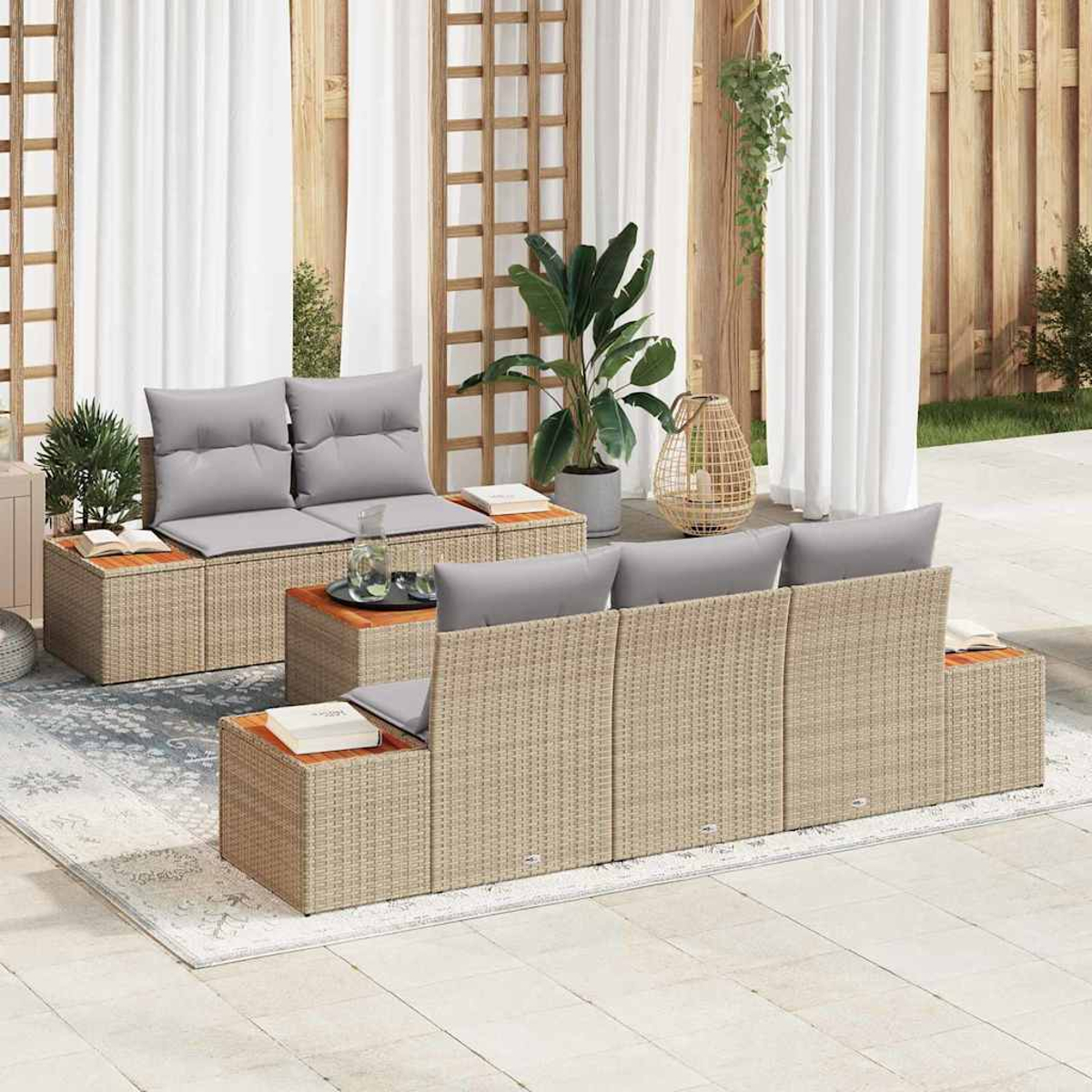Gartensitzgruppe mit beigen Rattansofas, grauen Kissen, Holztischen, Pflanzen und weißen Vorhängen im Hintergrund.