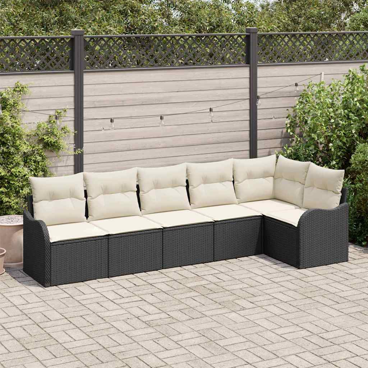 Ein Ecksofa im Freien mit cremefarbenen Kissen auf einer Ziegelpflasterung. Ein Holzzaun und Grünzeug sind im Hintergrund.