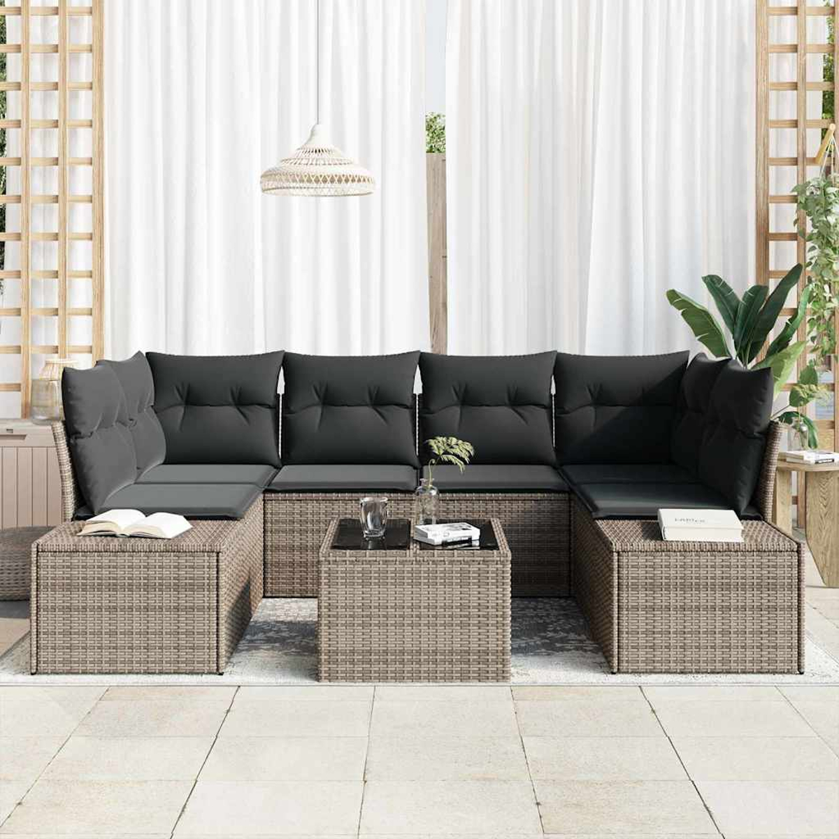 Outdoor-Ecksofa mit grauen Kissen und Korbgewebe. Ein kleiner Tisch mit Pflanzen und einem Buch ist sichtbar.