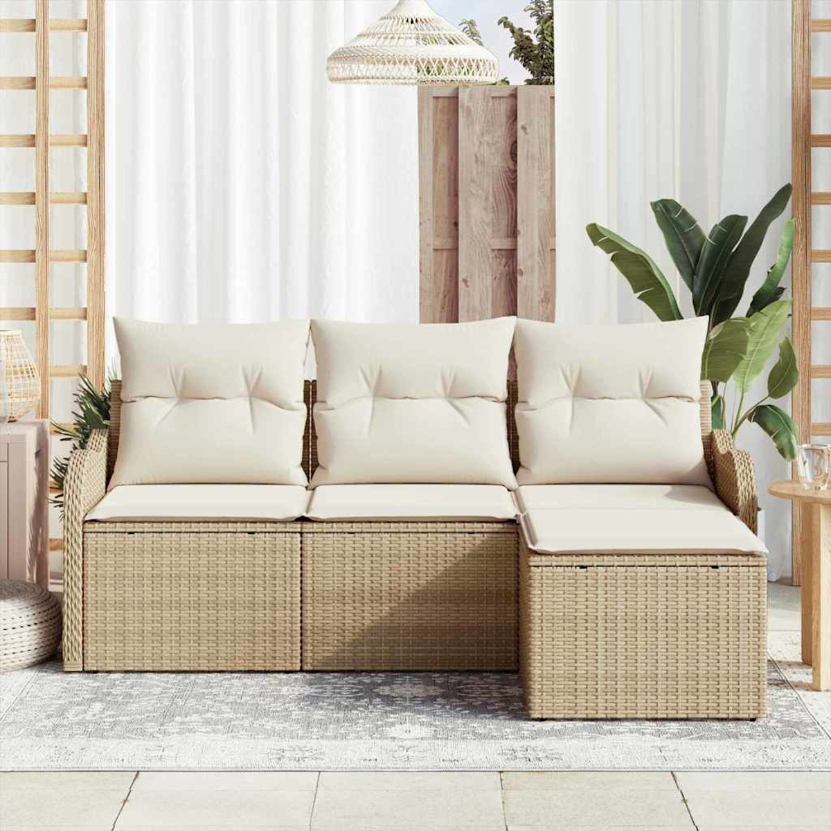 Ein geflochtenes Outdoor-Ecksofa mit cremefarbenen Kissen steht auf einem Teppich. Dahinter befinden sich ein weißer Vorhang, ein Holzzaun und eine Hängelampe.