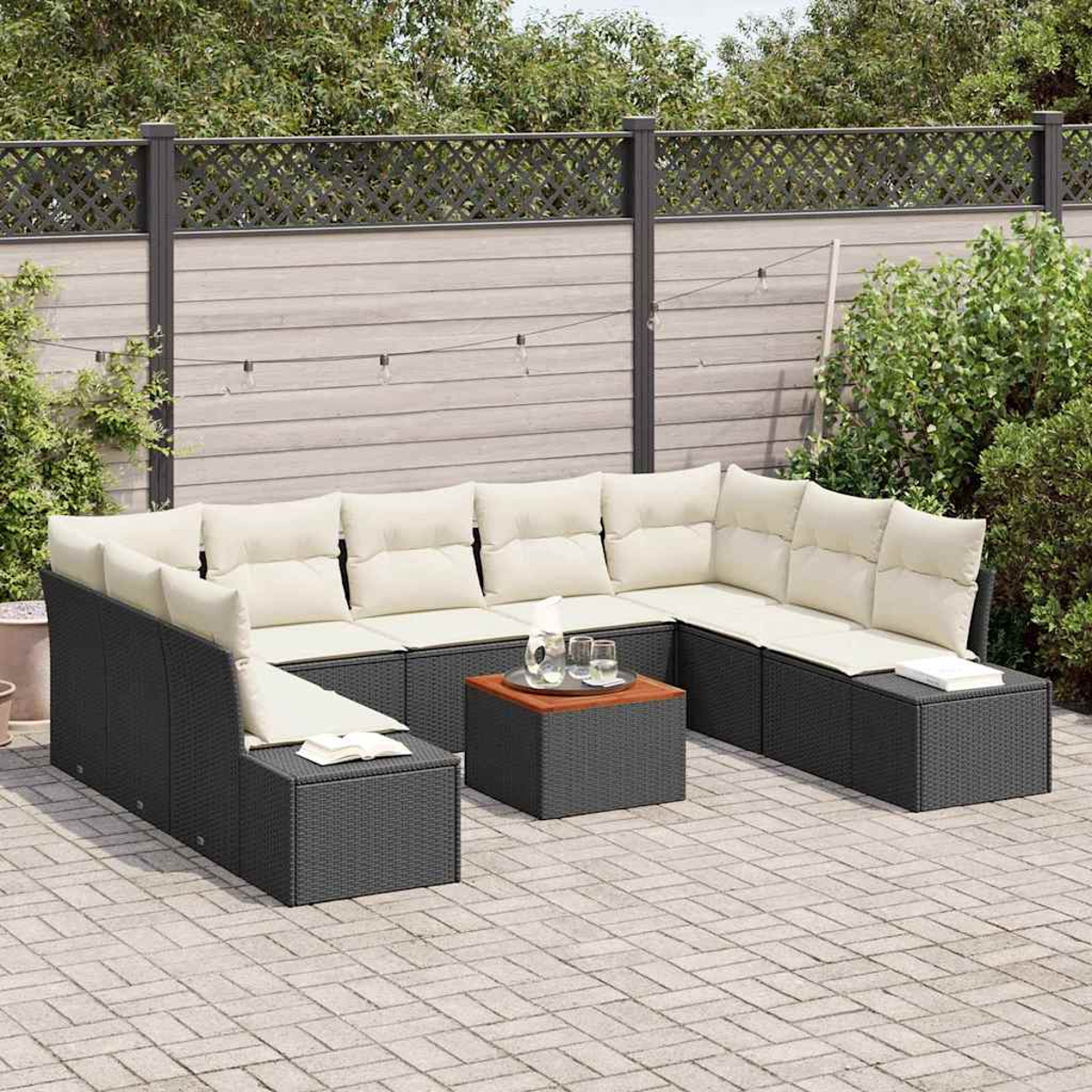 Outdoor-Ecksofa mit cremefarbenen Kissen, Couchtisch und dekorativem Zaun. Auf einer gepflasterten Terrasse mit Grün im Hintergrund.