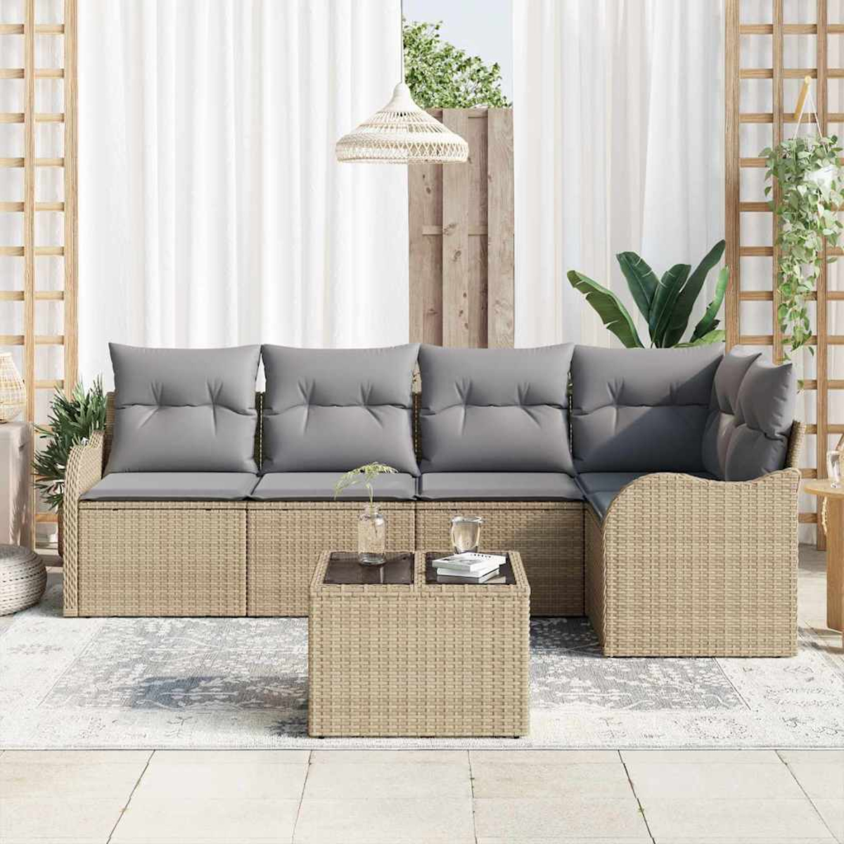 Gartenlounge-Set mit hellbraunem Korbmöbel-Sofa und Couchtisch. Graue Kissen, weiße Vorhänge und Pflanzen vervollständigen die Szene.