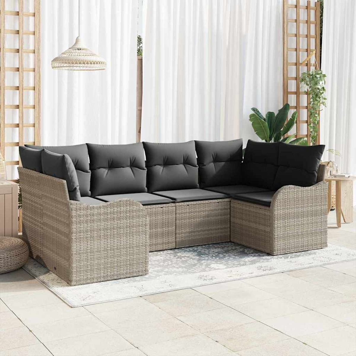 Outdoor-Ecksofa mit grauen Kissen auf einem gemusterten Teppich, in der Nähe von weißen Vorhängen und Holzgitter. Eine gewebte Lampe hängt oben.
