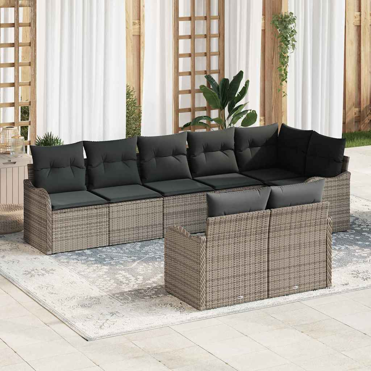 Outdoor-Rattansofa mit grauen Kissen. Weiße Vorhänge und Holzrahmen im Hintergrund. Teppich auf dem Boden.