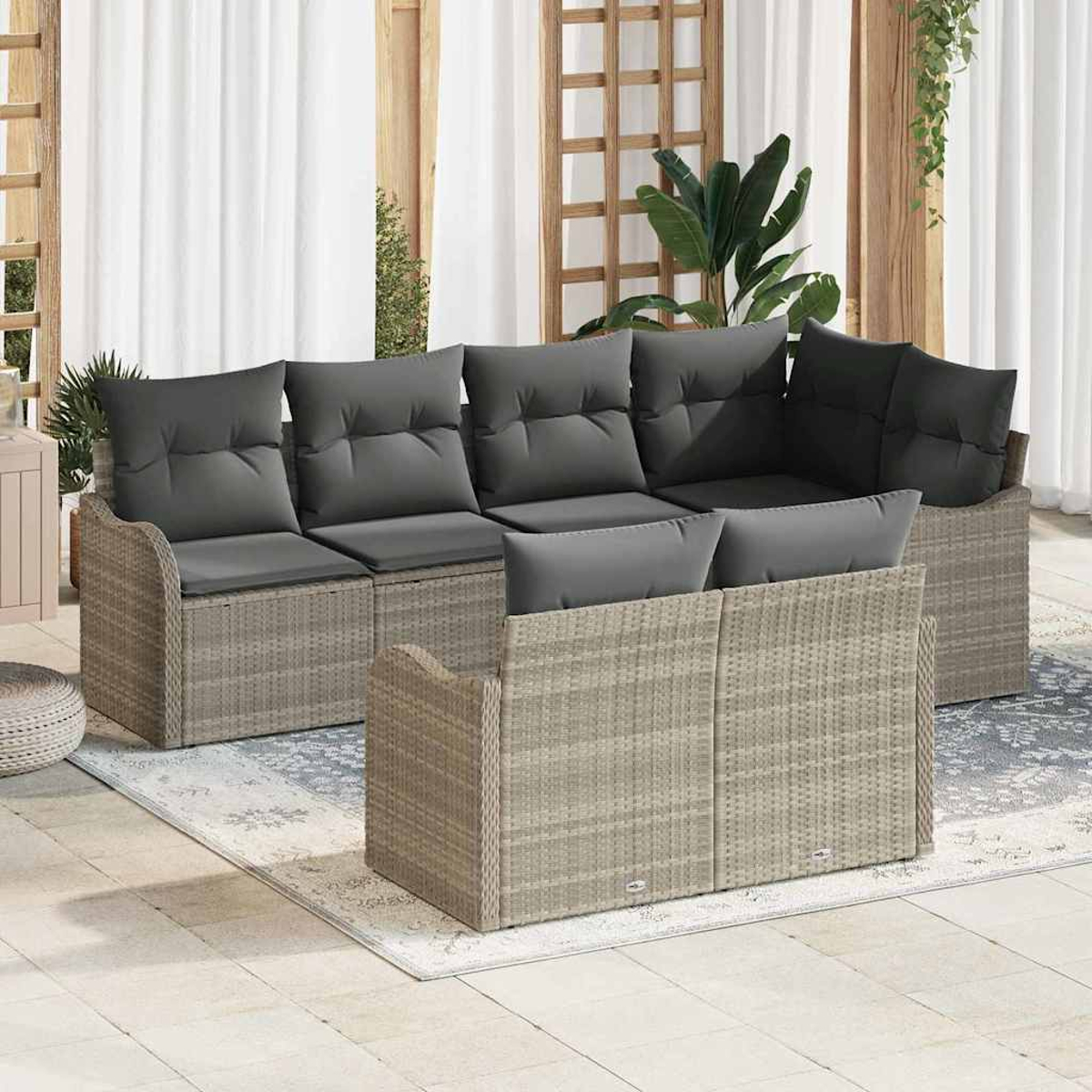 Outdoor-Korbsitzgruppe mit grauen Kissen. Das Set umfasst ein Ecksofa und ein Zweisitzer-Sofa auf einem Teppich.