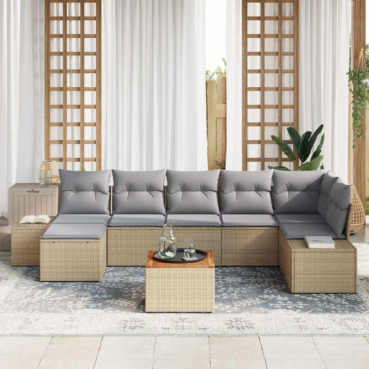 Rattansofa im Freien mit grauen Kissen, quadratischem Tisch mit Tablett und Teppich. Weiße Vorhänge und hölzerner Spalier im Hintergrund.