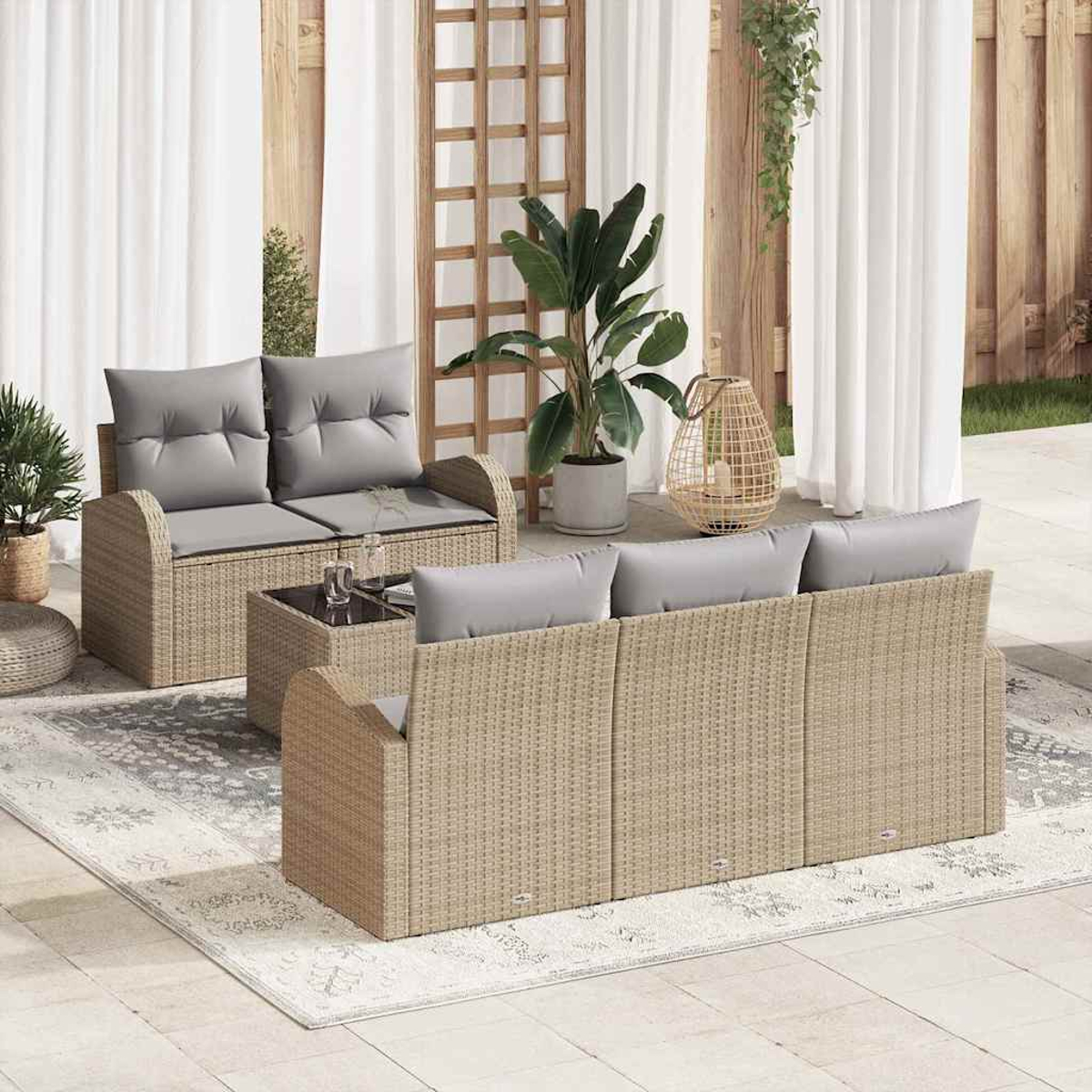 Garten-Sitzgruppe auf einer Terrasse. Sie verfügt über ein Korbmöbel-Sofa und -Liege mit grauen Kissen, einen kleinen Tisch und Pflanzen.