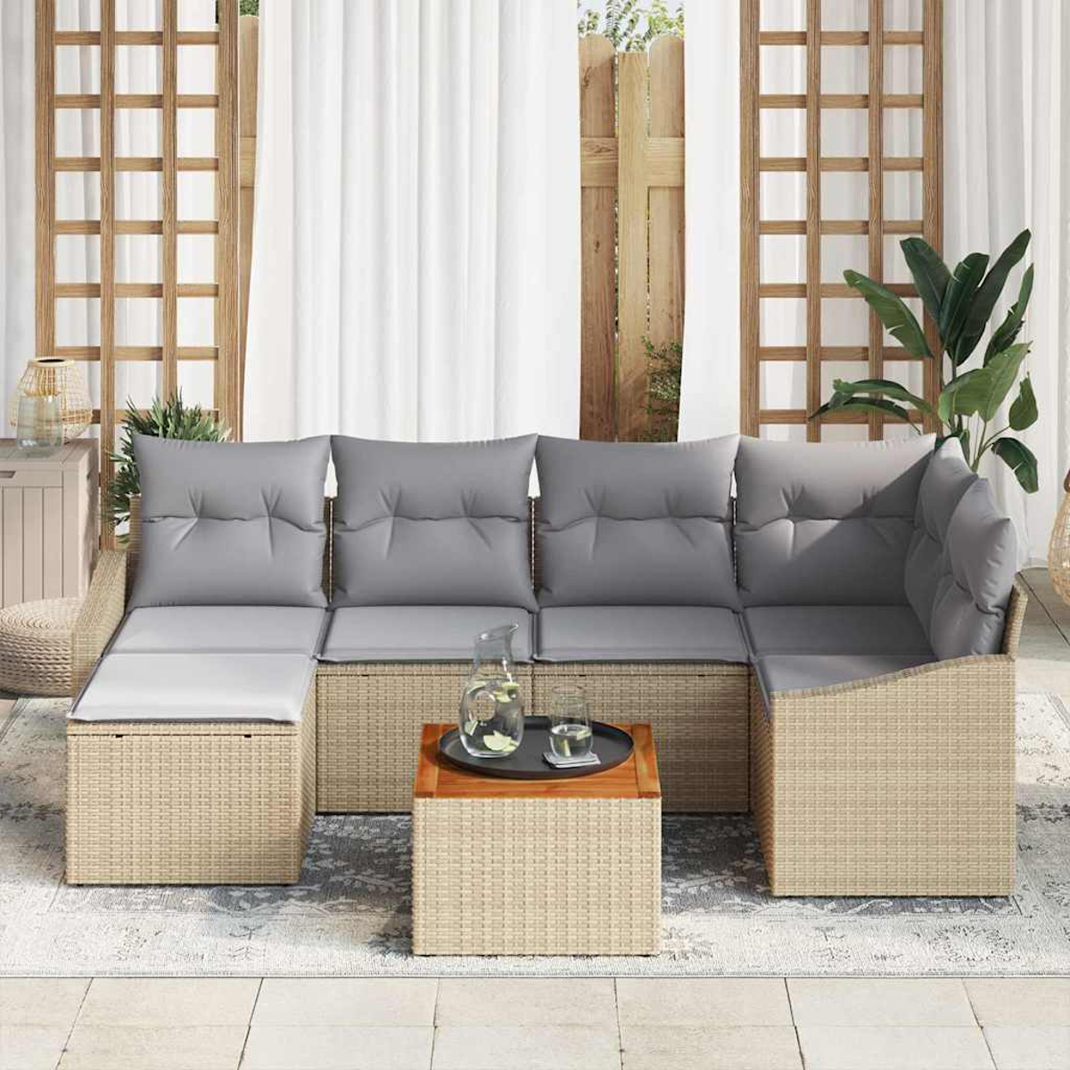Ein Ecksofa im Freien mit grauen Kissen. Ein Holztisch mit Tablett und Glas Wasser. Weiße Vorhänge und eine Pflanze sind sichtbar.