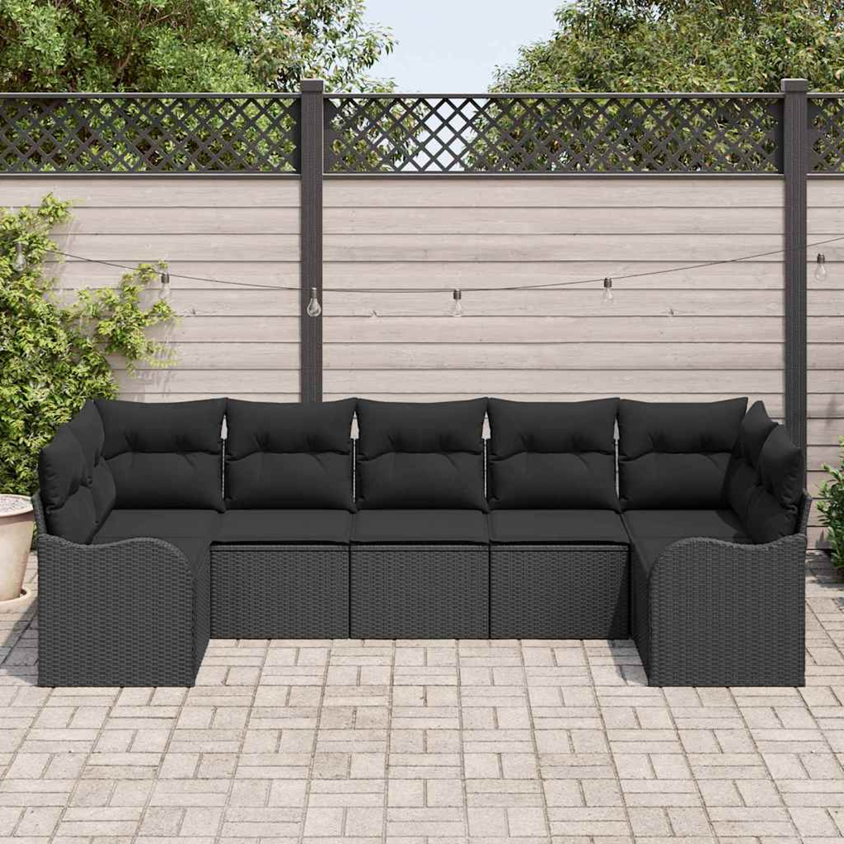 Dunkelgraues Ecksofa mit schwarzen Kissen auf einer gepflasterten Terrasse. Im Hintergrund ein Holzzaun mit Zieraufsatz.