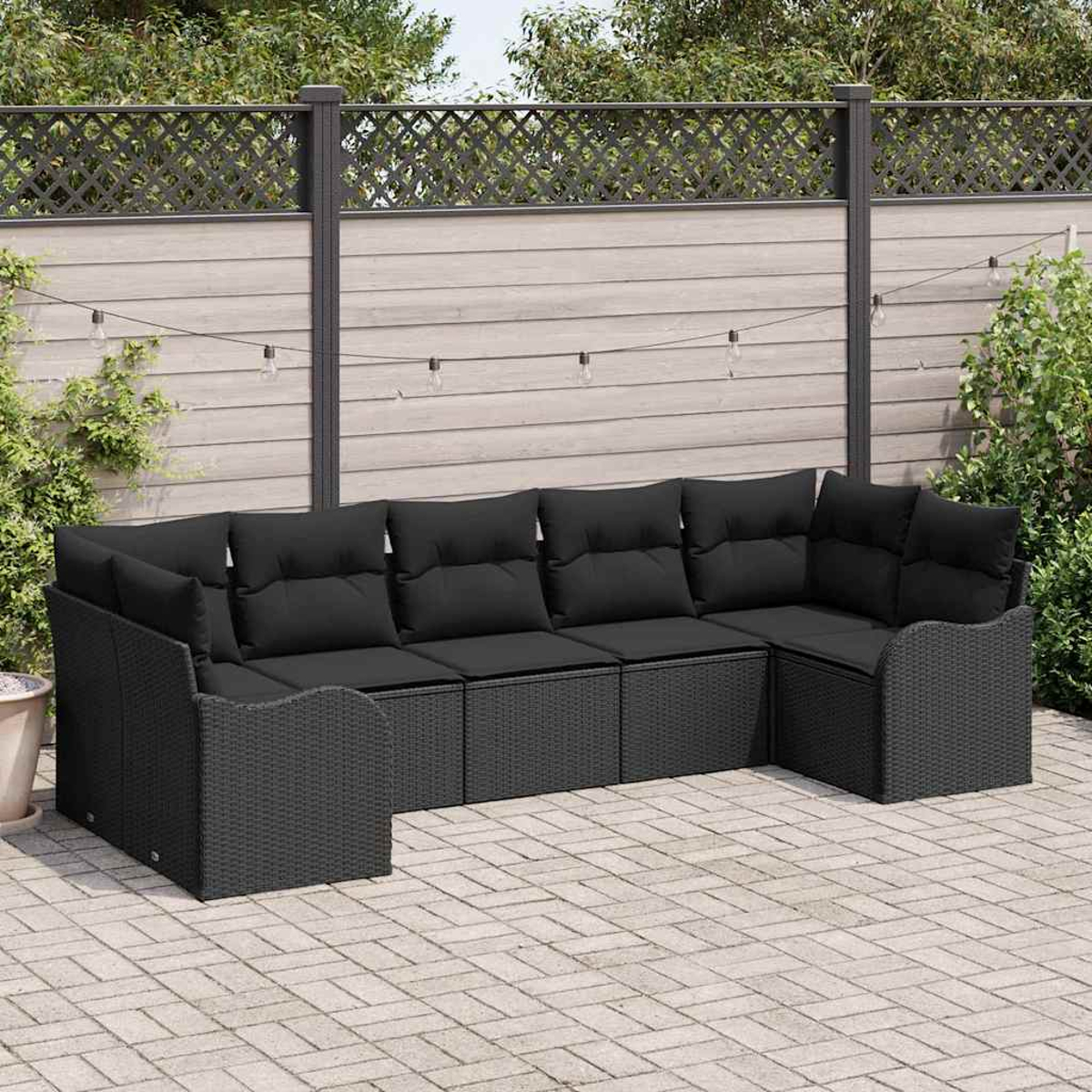 Ein schwarzes Ecksofa aus Korbgeflecht mit schwarzen Kissen steht auf einer Backstein-Terrasse. Dahinter ein Holzzaun mit dekorativer Spitze.