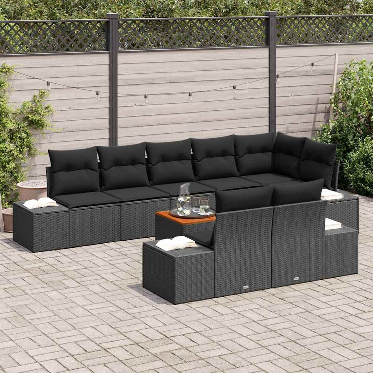 Outdoor-Ecksofa mit schwarzen Kissen und Beistelltischen. Ein Holztisch mit Getränken steht vor dem Sofa. Im Hintergrund ist ein Zaun.
