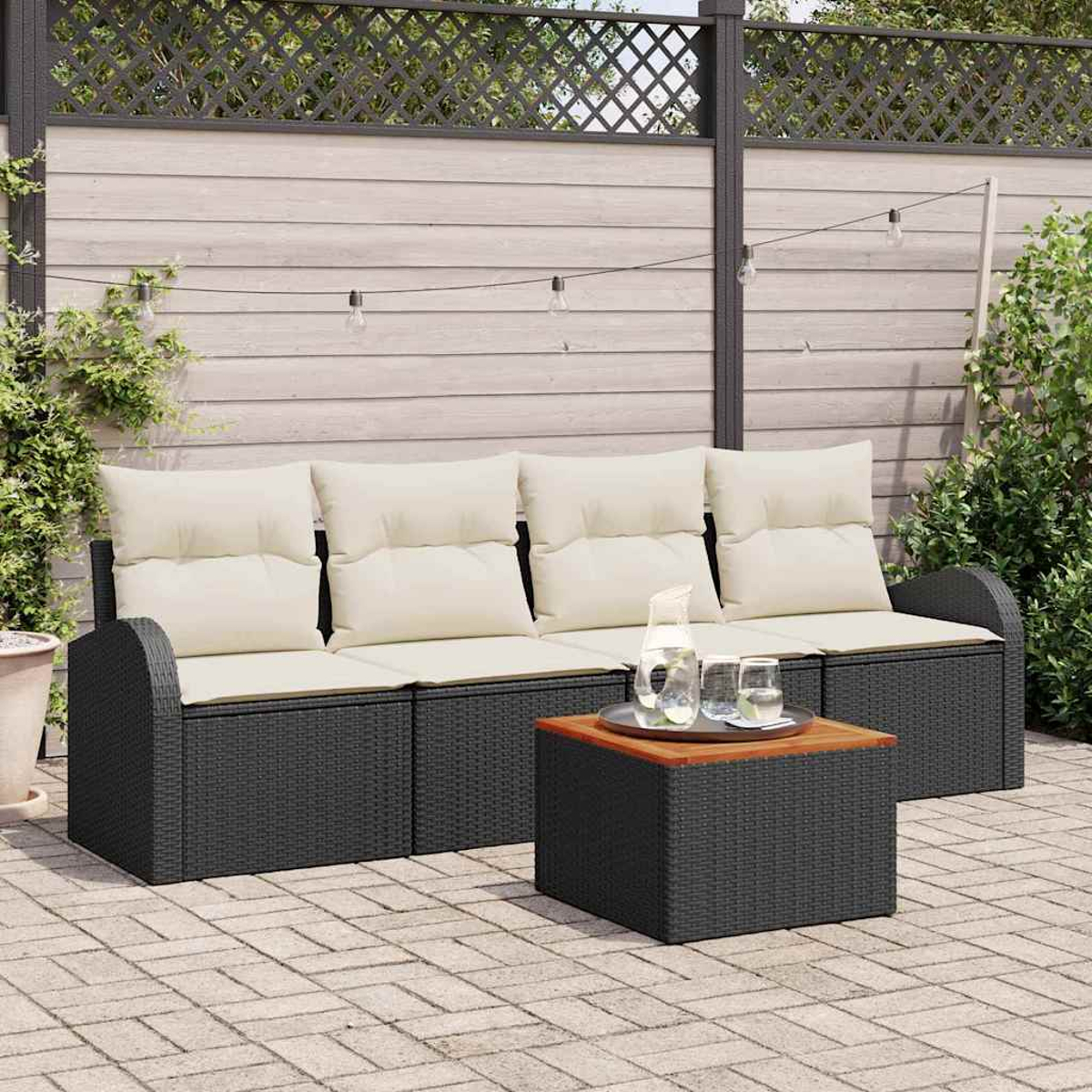Terrassengarnitur: schwarzes Korbmöbel-Sofa mit cremefarbenen Kissen, kleiner Holztisch mit Getränken, vor Holzzaun.