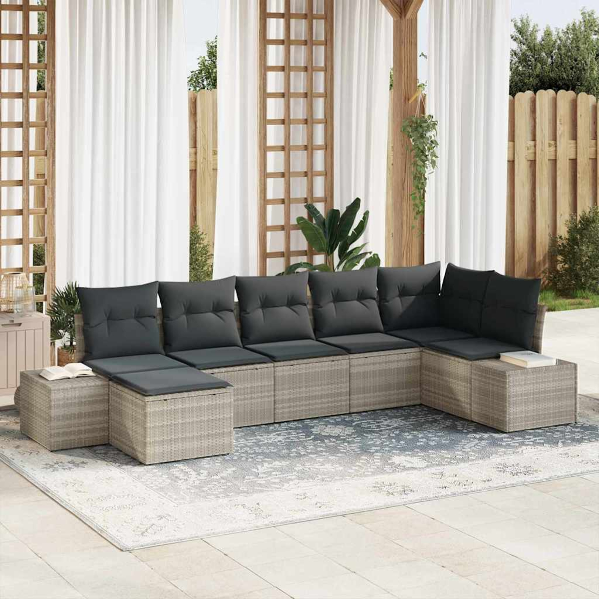 Outdoor-Ecksofa mit grauen Kissen auf einer Terrasse. Weiße Vorhänge, Holzgitter und Grün im Hintergrund.