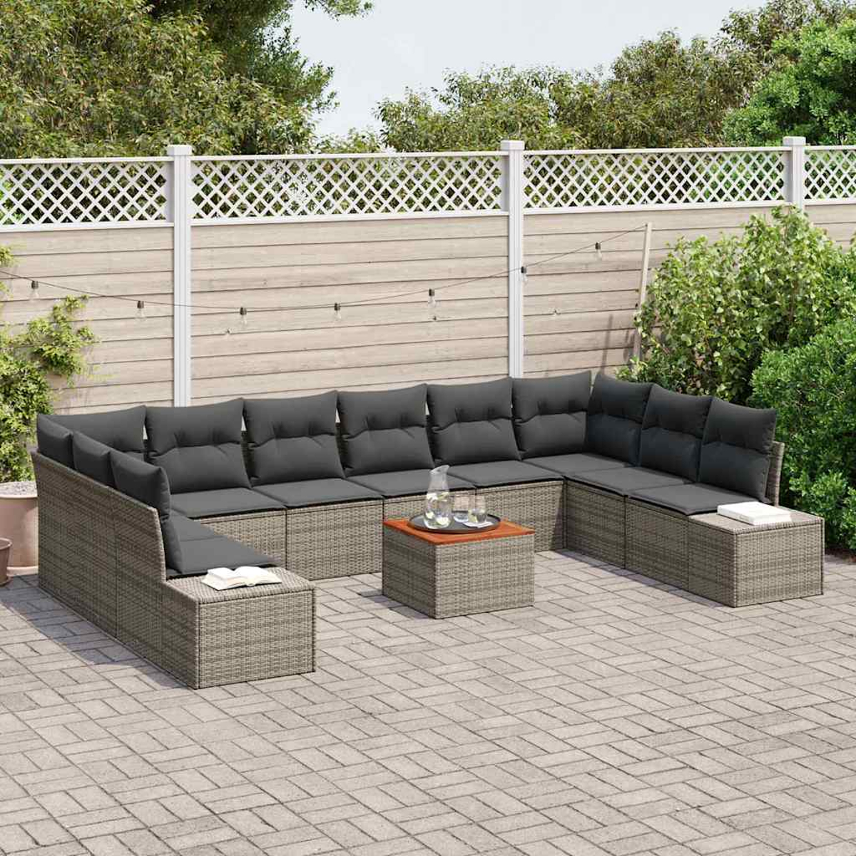 Un sofá seccional de ratán gris con cojines gris oscuro y una mesa pequeña con bebidas en un patio de ladrillo en un jardín.