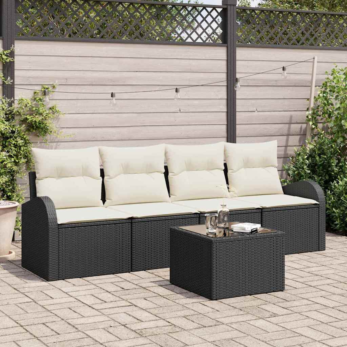 Szene im Freien mit einem schwarzen Korbsessel mit cremefarbenen Kissen und einem passenden Tisch auf einer Ziegelterrasse. Der Hintergrund umfasst einen Zaun.