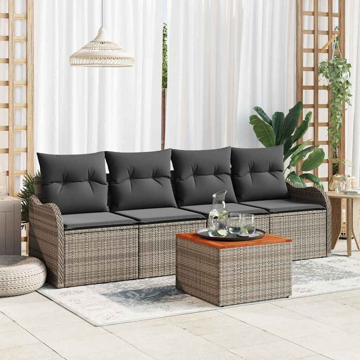 Gartenmöbel mit grauen Kissen und einem Couchtisch. Dahinter weiße Vorhänge und Pflanzen. Eine Hängelampe ist ebenfalls zu sehen.