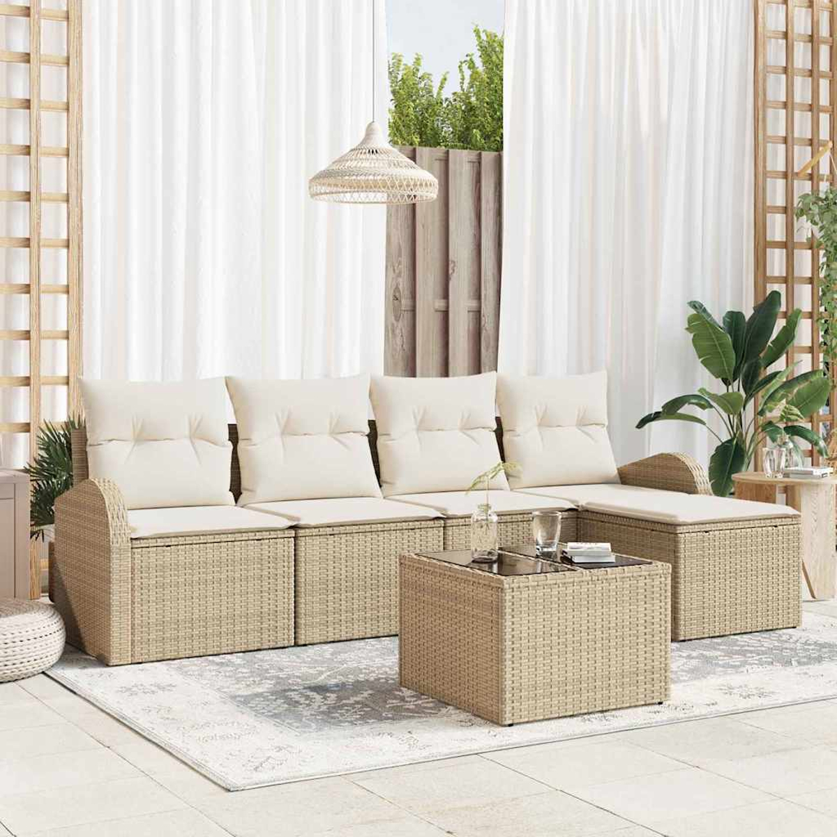 Rattansofa-Set für den Außenbereich mit cremefarbenen Kissen. Ein passender Couchtisch mit Glasplatte steht auf einem gemusterten Teppich.