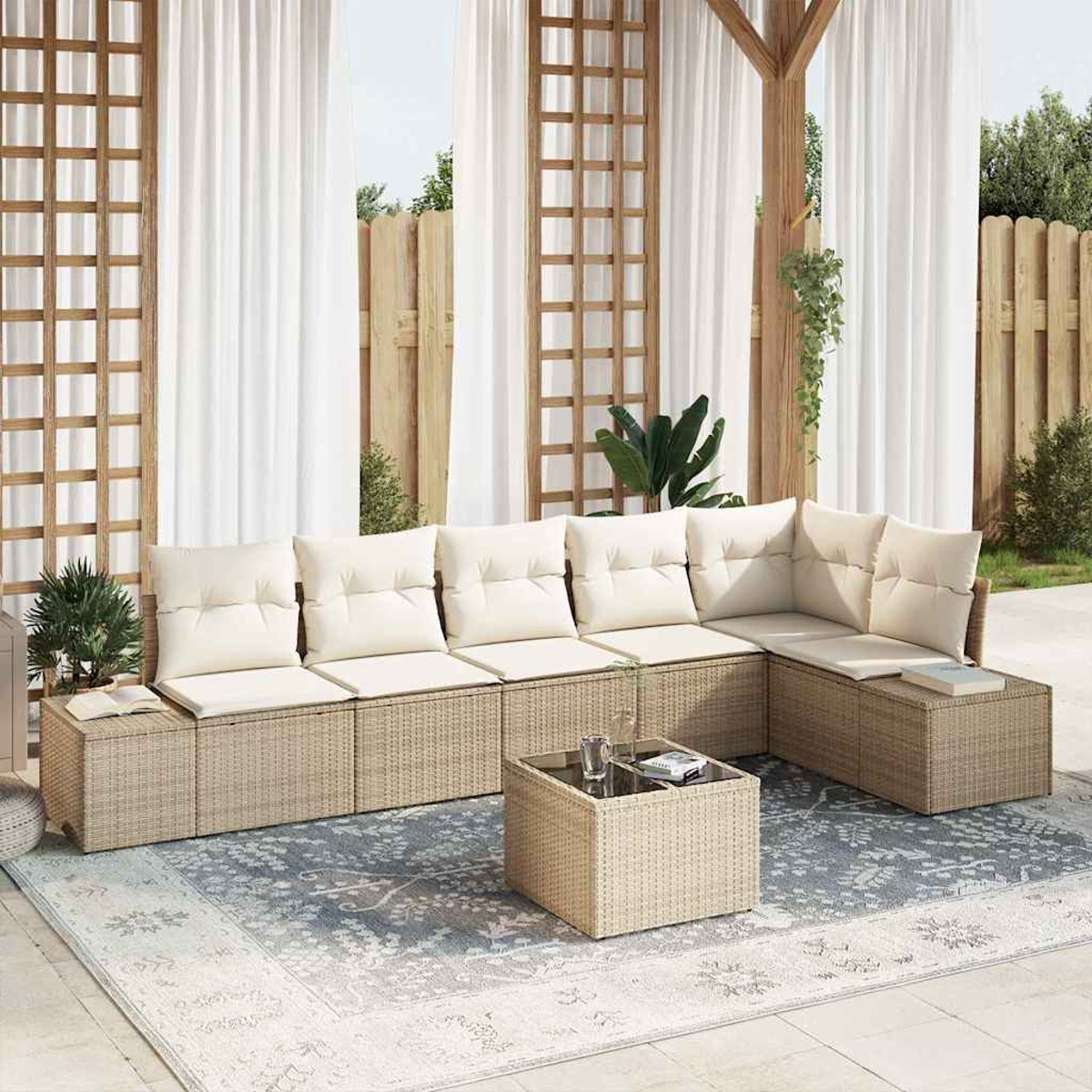 Gartensektionssofa mit cremefarbenen Kissen und einem Couchtisch auf einem Teppich, vor Vorhängen und einem Holzzaun.