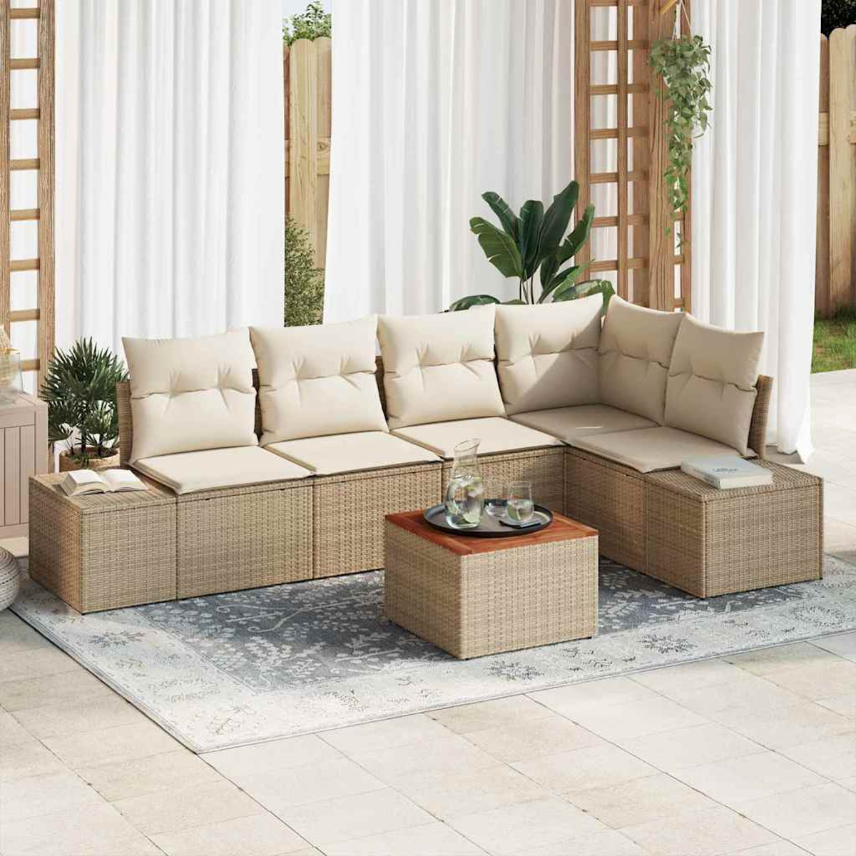 Sof á de mimbre para exteriores con cojines beige. Una mesa pequeña con bebidas sobre una alfombra. Cortinas blancas y plantas al fondo.