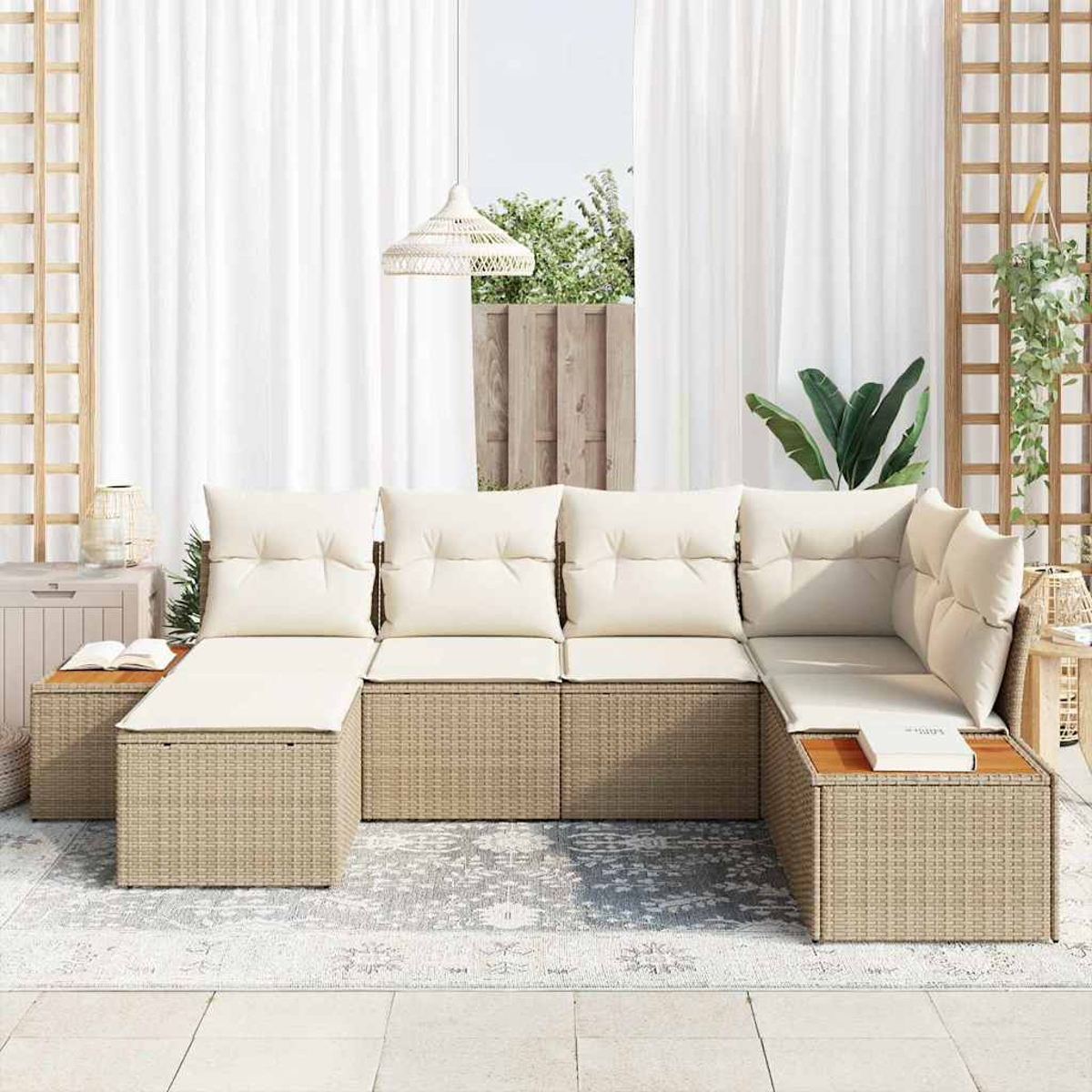 Outdoor-Rattansofa mit cremefarbenen Kissen, einem kleinen Tisch mit einem Buch und weißen Vorhängen im Hintergrund. Die Szene ist hell.