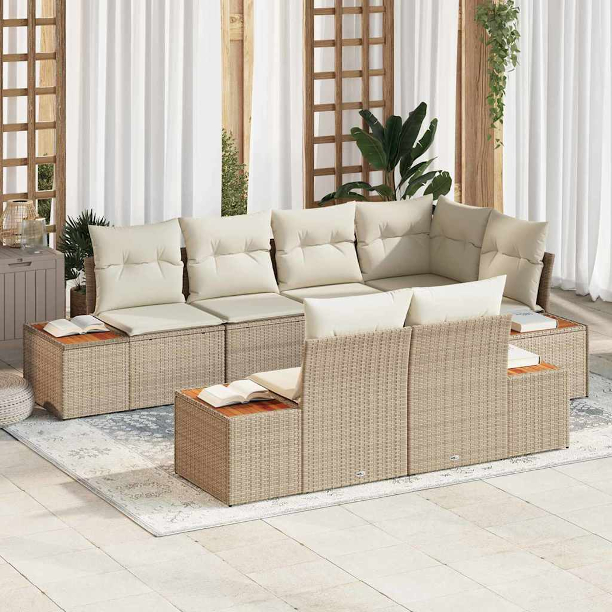 Ein Rattansofa für den Außenbereich mit cremefarbenen Kissen. Es steht auf einem gemusterten Teppich vor weißen Vorhängen.