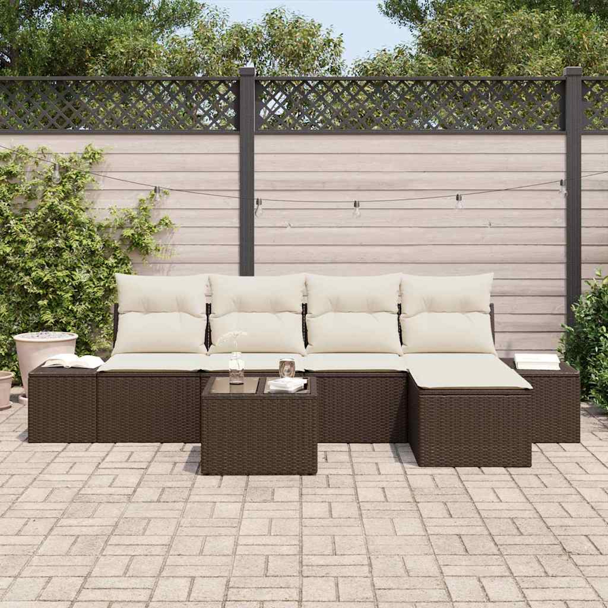 Outdoor-Ecksofa mit cremefarbenen Kissen und einem kleinen Tisch. Auf einer Backstein-Terrasse mit Holzzaun im Hintergrund.