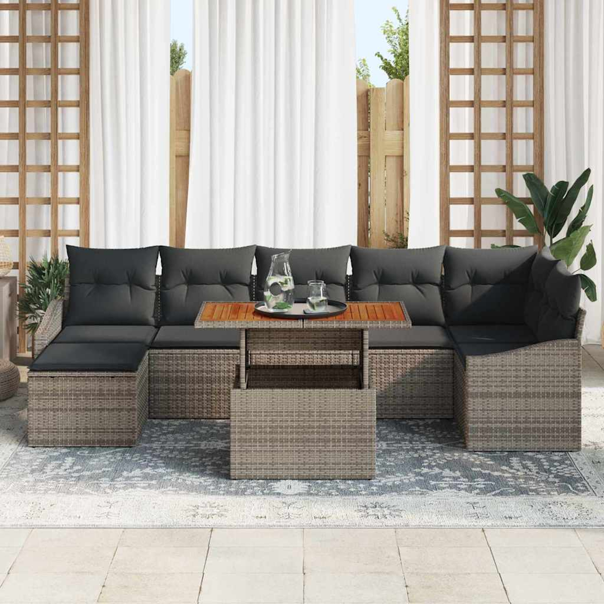 Gartensofa mit grauen Kissen und einem Holztisch mit Getränken. Weiße Vorhänge und Pflanzen sind im Hintergrund zu sehen.