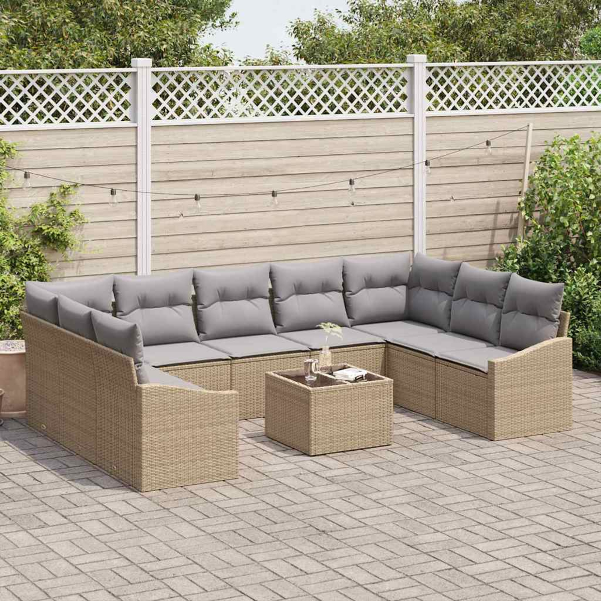 Ein Ecksofa im Freien mit grauen Kissen und einem kleinen Tisch steht auf einer Terrasse. Ein weißer Zaun und grüne Pflanzen sind im Hintergrund.