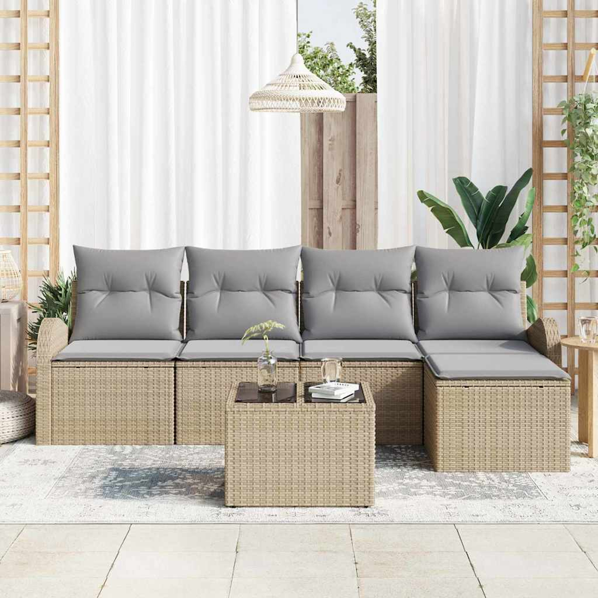 Garten-Sitzgruppe mit grauen Kissen, passendem Couchtisch und weißen Vorhängen im Hintergrund.