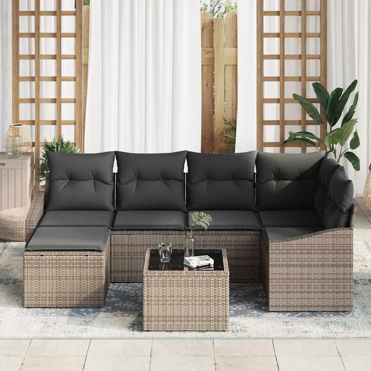 Outdoor-Ecksofa mit schwarzen Kissen und Couchtisch. Der Hintergrund umfasst ein Fenster, weiße Vorhänge und Pflanzen.