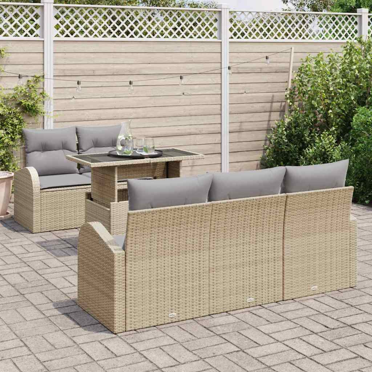 Gartenmöbelset: Korbsessel und -sofa mit grauen Kissen, Tisch und weißem Zaun im Hintergrund. Umgebung im Freien.