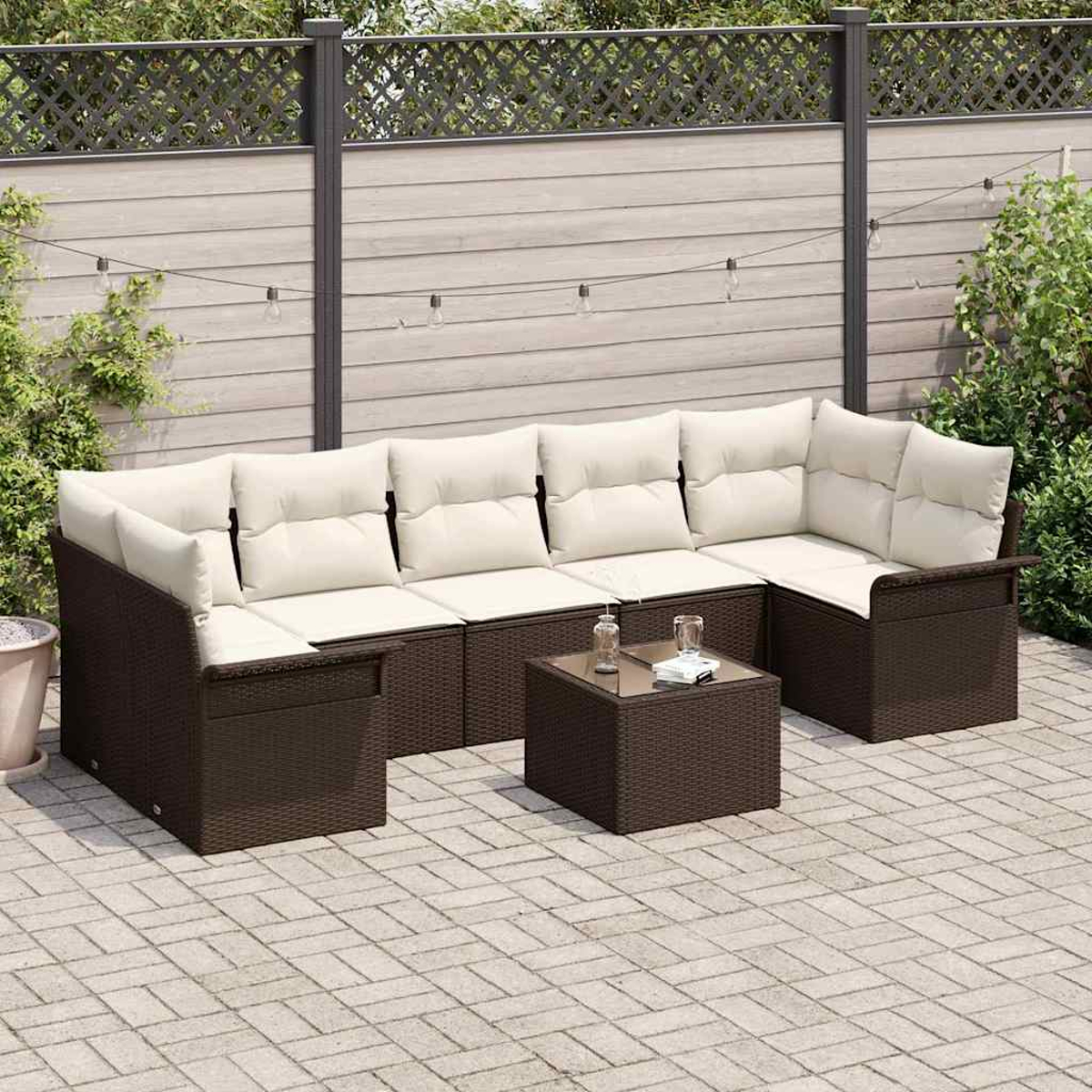 Eine Sitzgruppe im Freien mit einem braunen Korbsessel und -tisch, cremefarbenen Kissen, auf einer gepflasterten Terrasse, mit Zaun und Grün im Hintergrund.